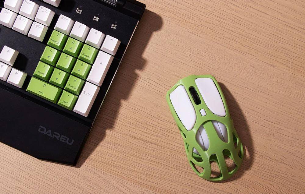 Eine Numerische Tastatur mit weißen und grünen Tasten liegt neben einer weißen und grünen Computermaus mit einem charakteristischen Ausschnitt-Design auf einer Holzoberfläche.