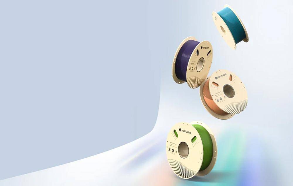 Vier Spulen mit unterschiedlich gefärbtem 3D-Druckfilament (türkis, lila, braun, grün) vor einem hellen Hintergrund angeordnet.