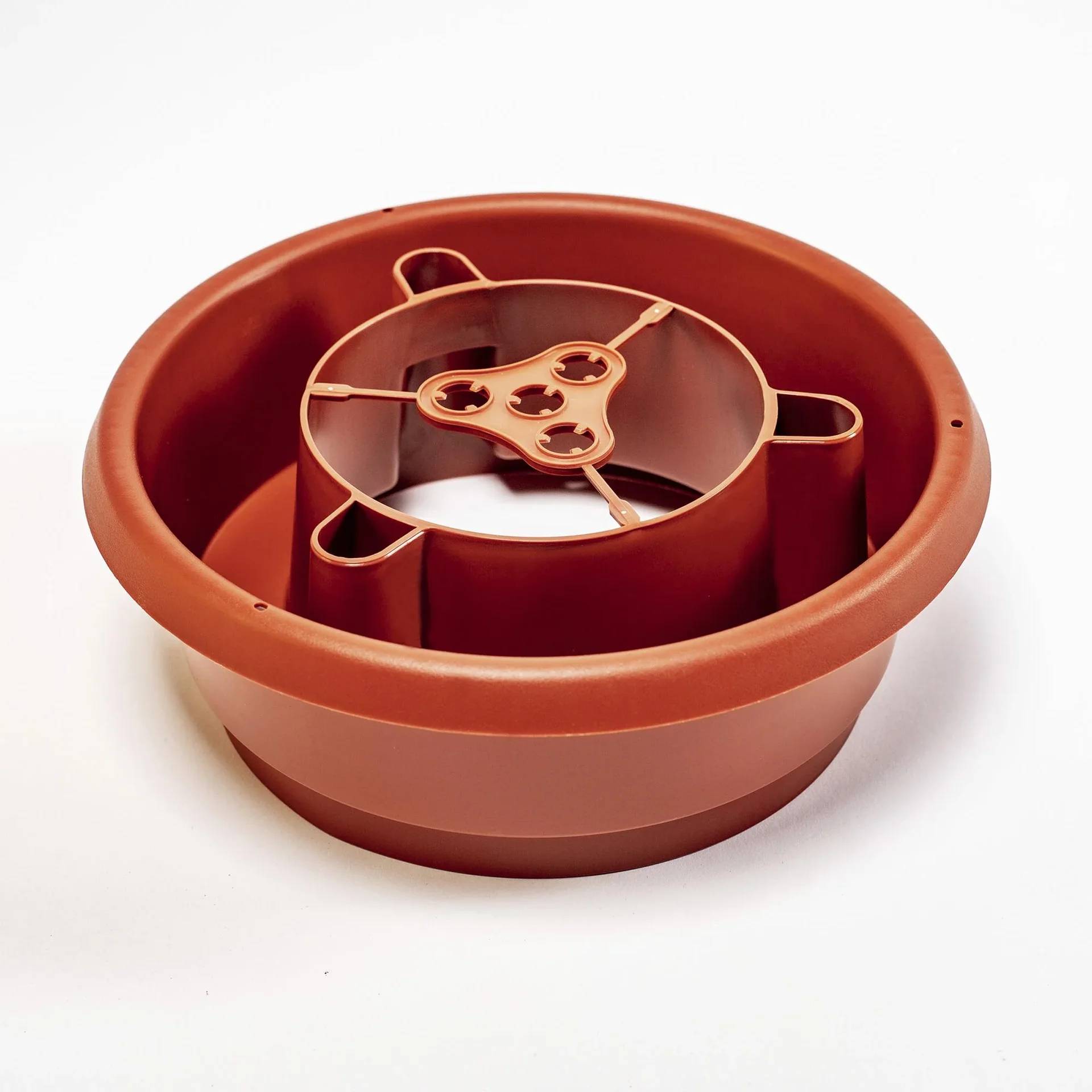 Ein terrakottafarbener Kunststoff-Untersetzer mit integriertem Wasserreservoir und erhöhtem Pflanzenhalter. Geeignet für den Innen- und Außenbereich.