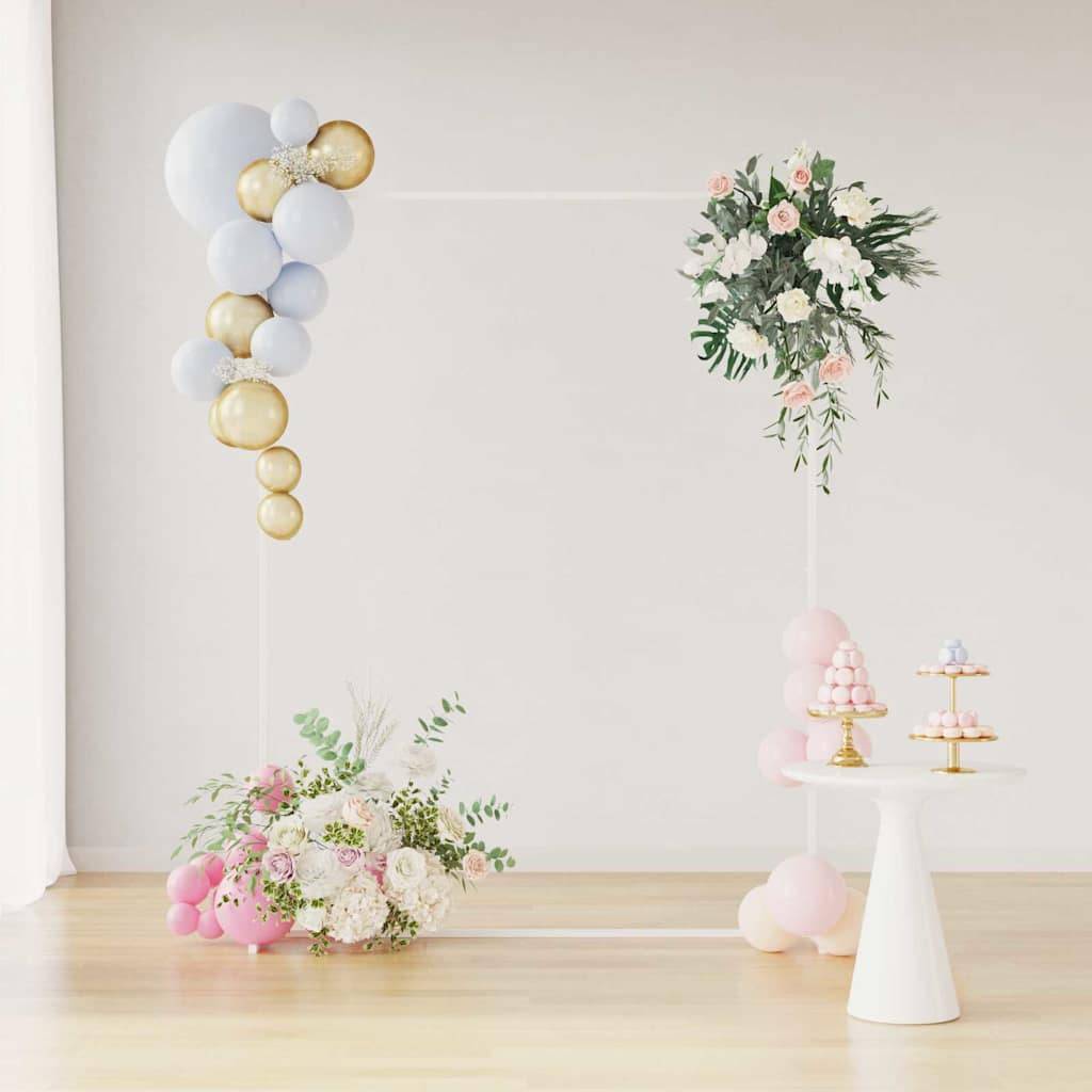 Eine dekorative Blumengestaltung mit pastellfarbenen Luftballons, Blumen und einem kleinen weißen Tisch mit Desserts. Elegante, festliche Atmosphäre.