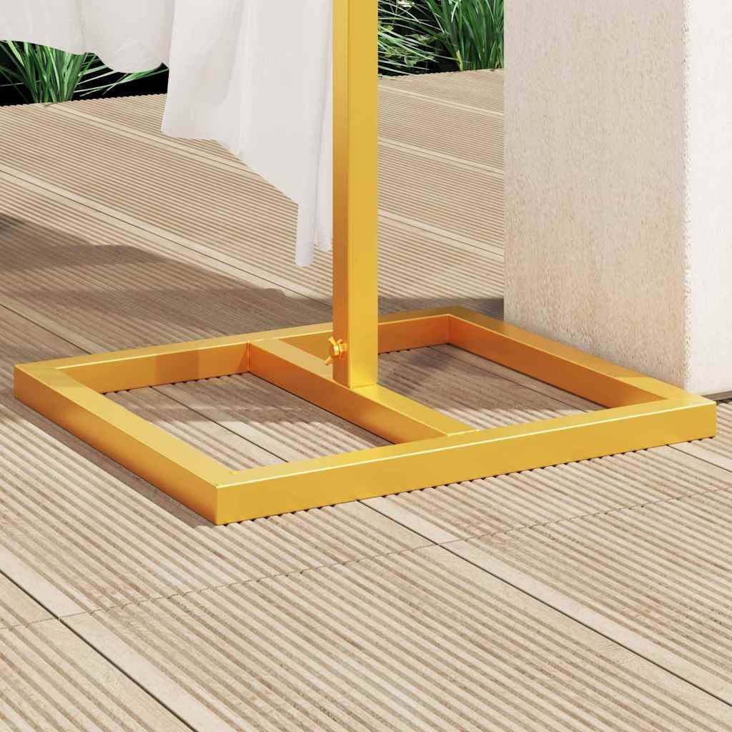 Ein gelbes Handtuchgestell steht auf einer Holzterrasse. Ein weißes Handtuch hängt am Gestell, positioniert neben einer beigen Wand, an der grüne Blätter zu sehen sind.