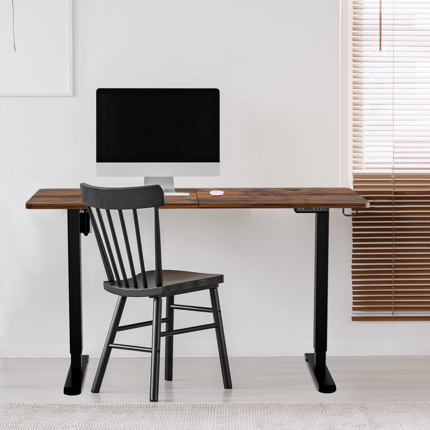 Eine moderne Home-Office-Einrichtung mit einem Holzschreibtisch, einem schwarzen Stuhl, einem Computermonitor und minimalistischen Dekorationen. Ein helles Fensterrollo filtert das Sonnenlicht.