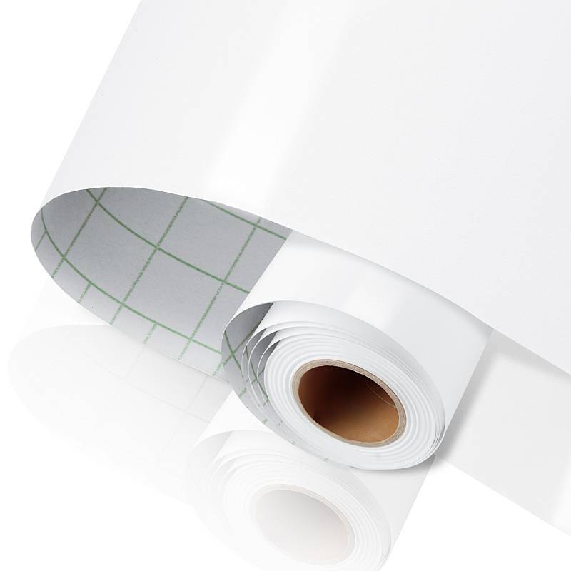 Eine Rolle glänzendes, weißes Selbstklebevinylpapier, teilweise ausgerollt und mit einem Raster auf der Rückseite zur einfachen Schnitt- und Maßbestimmung.