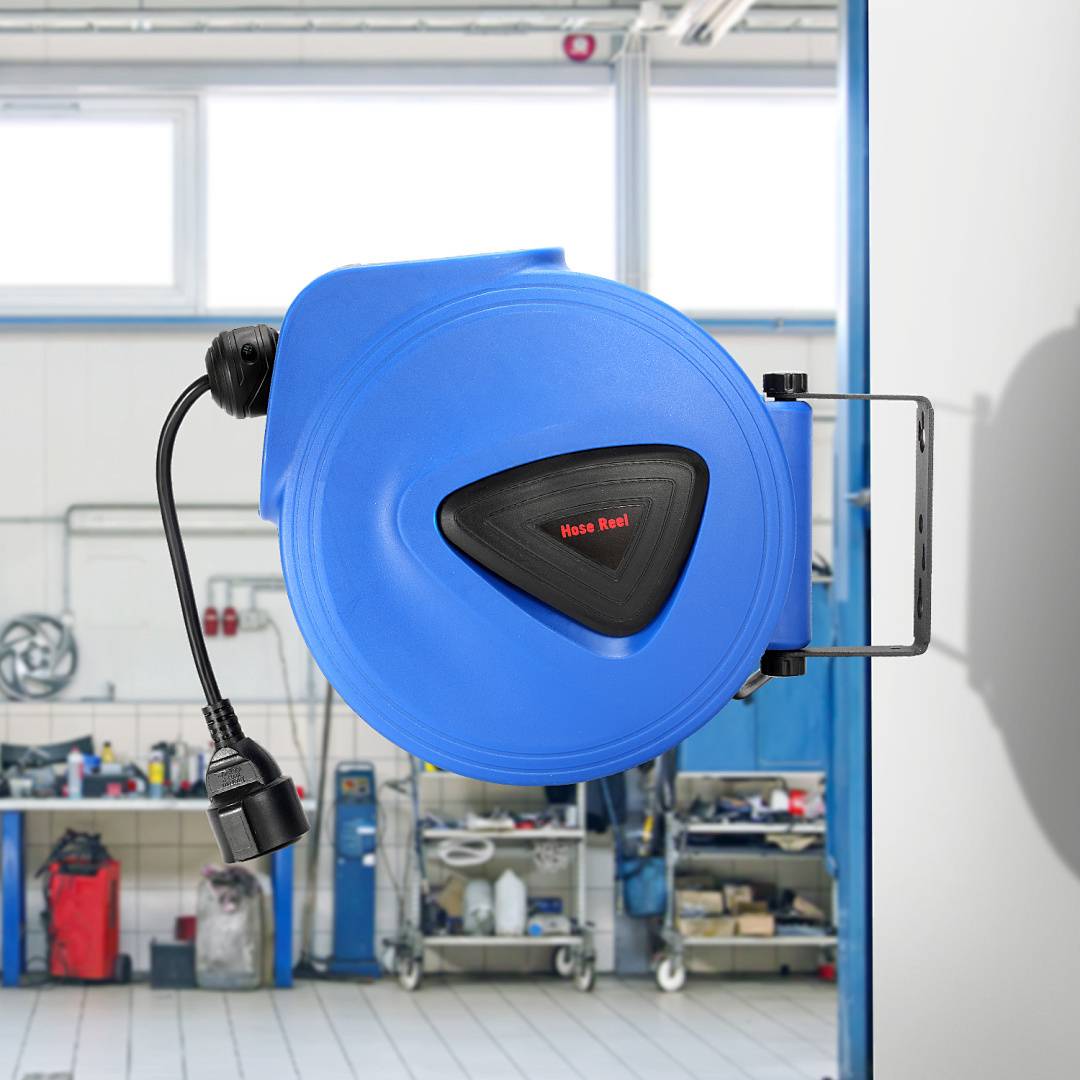 Eine blaue einziehbare Schlauchtrommel, die an einer Werkstattwand montiert ist, mit Werkzeugen und Ausrüstung im Hintergrund.