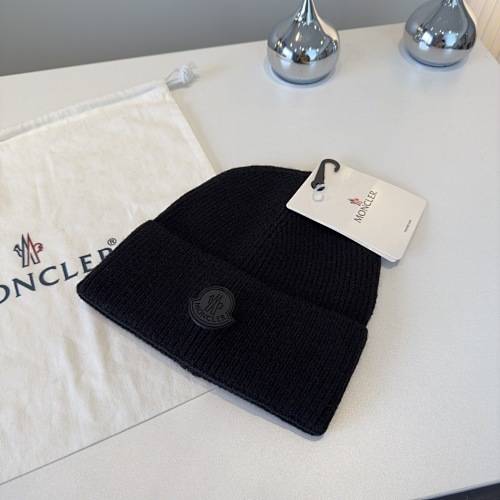 Eine schwarze Strickmütze mit Moncler-Logo auf einer weißen Oberfläche neben einer Moncler-Marken-Zugbeutel und zwei chromfarbenen Objekten.