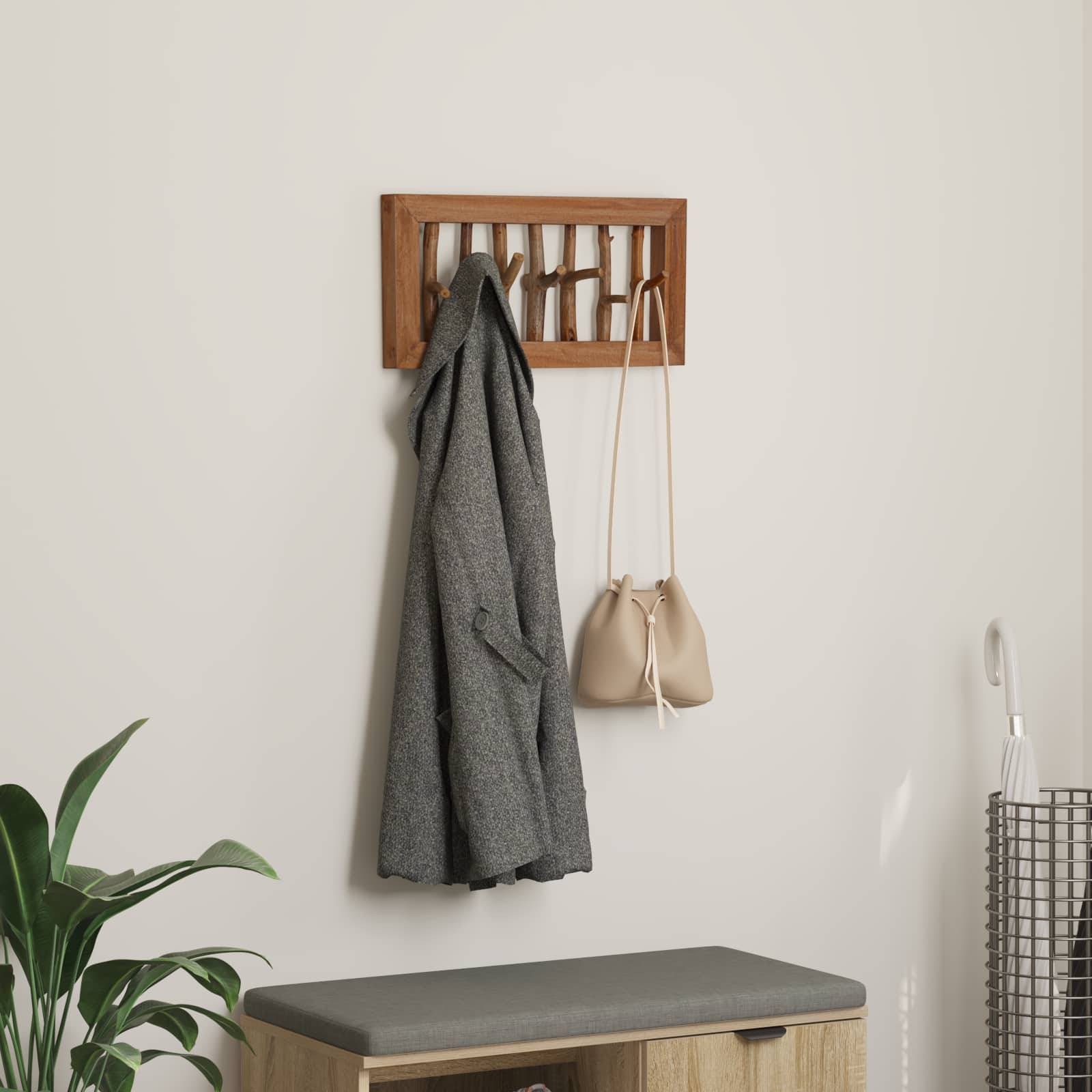 Ein Mantel und eine Handtasche hängen an einem Holzwandhalter über einer gepolsterten Bank. Eine Topfpflanze steht in der Ecke.