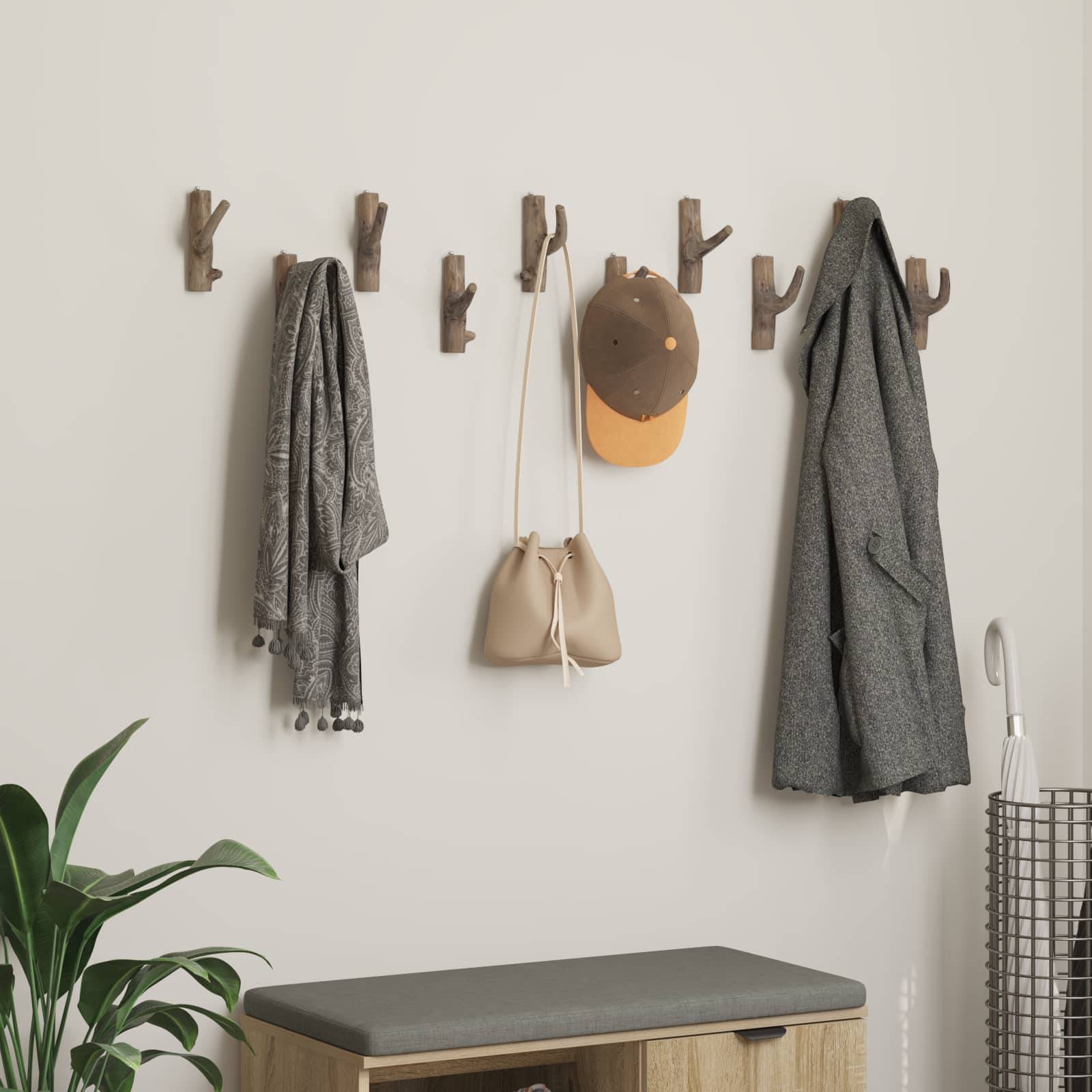 Gemütlicher Eingangsbereich mit Holzhaken, an denen ein Schal, eine Tasche, ein Hut und ein Mantel über einer Bank hängen. Einfache, organisierte Einrichtung mit einer Pflanze in der Nähe.