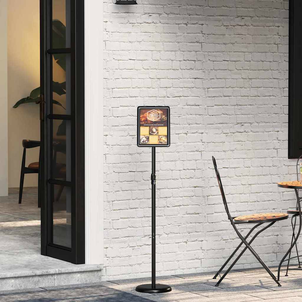 Außenbereich eines Cafés mit leeren Stühlen und Tischen auf einer Terrasse. Ein Ständer mit einer Speisekarte ist sichtbar, mit einer Pflanze in einem Gebäude im Hintergrund.