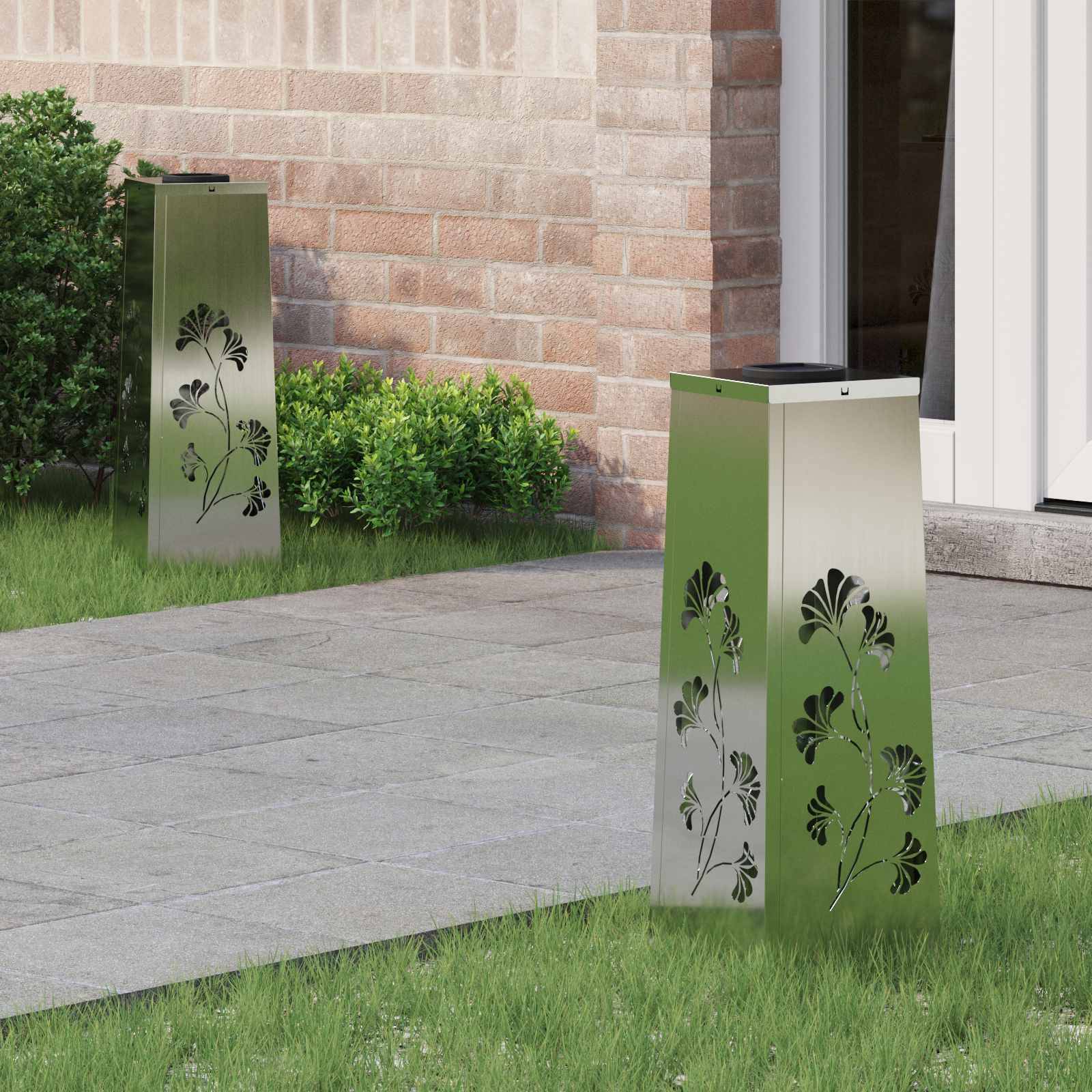 Zwei metallische Gartenleuchten mit Blumenmotiven auf einer Terrasse neben einer Backsteinmauer und grünen Sträuchern.