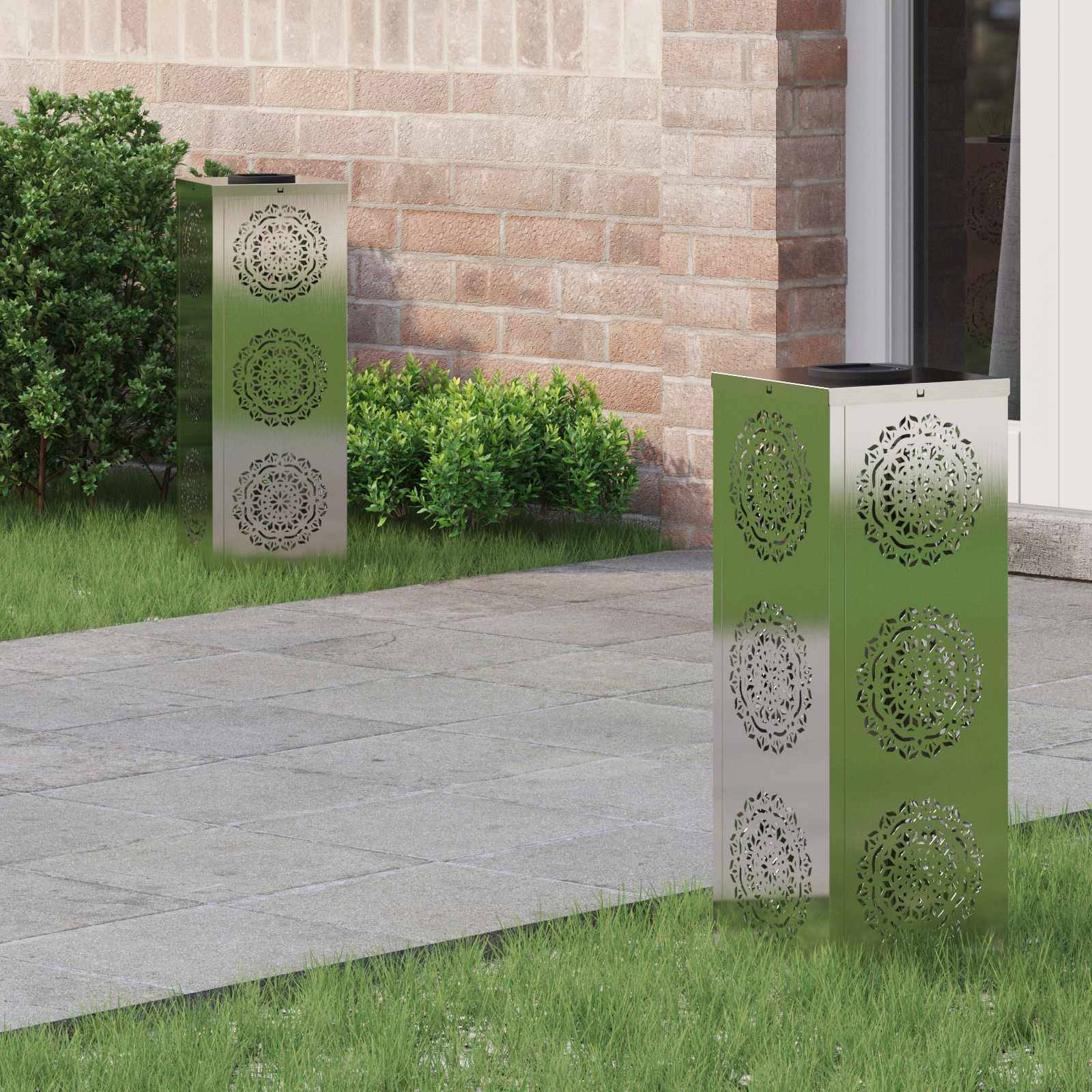 Metallische Gartenleuchten mit kunstvollen kreisförmigen Ausschnittmustern auf einem gefliesten Weg neben grünem Rasen und einer Ziegelwand.