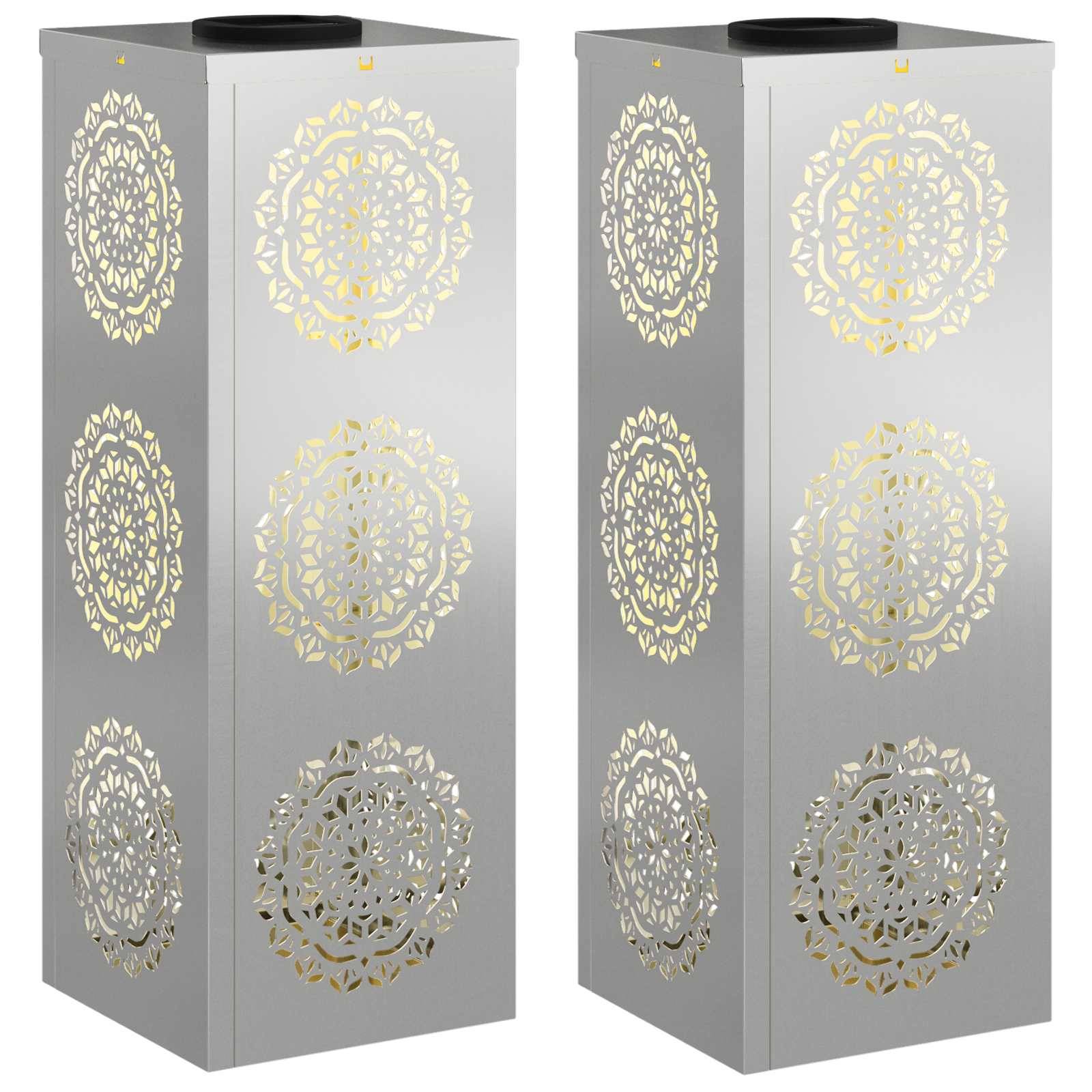 Zwei hohe, silberne Türme mit kunstvollen, kreisförmigen Ausschnittmustern in Gold. Sie stehen nebeneinander und reflektieren das Licht auf ihren glänzenden Oberflächen.