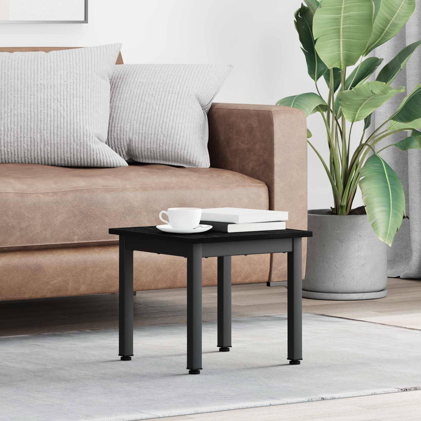 Ein modernes Wohnzimmer zeigt ein braunes Sofa mit gestreiften Kissen, einen kleinen schwarzen Couchtisch mit einer Tasse und einem Buch sowie eine Pflanze in der Nähe.