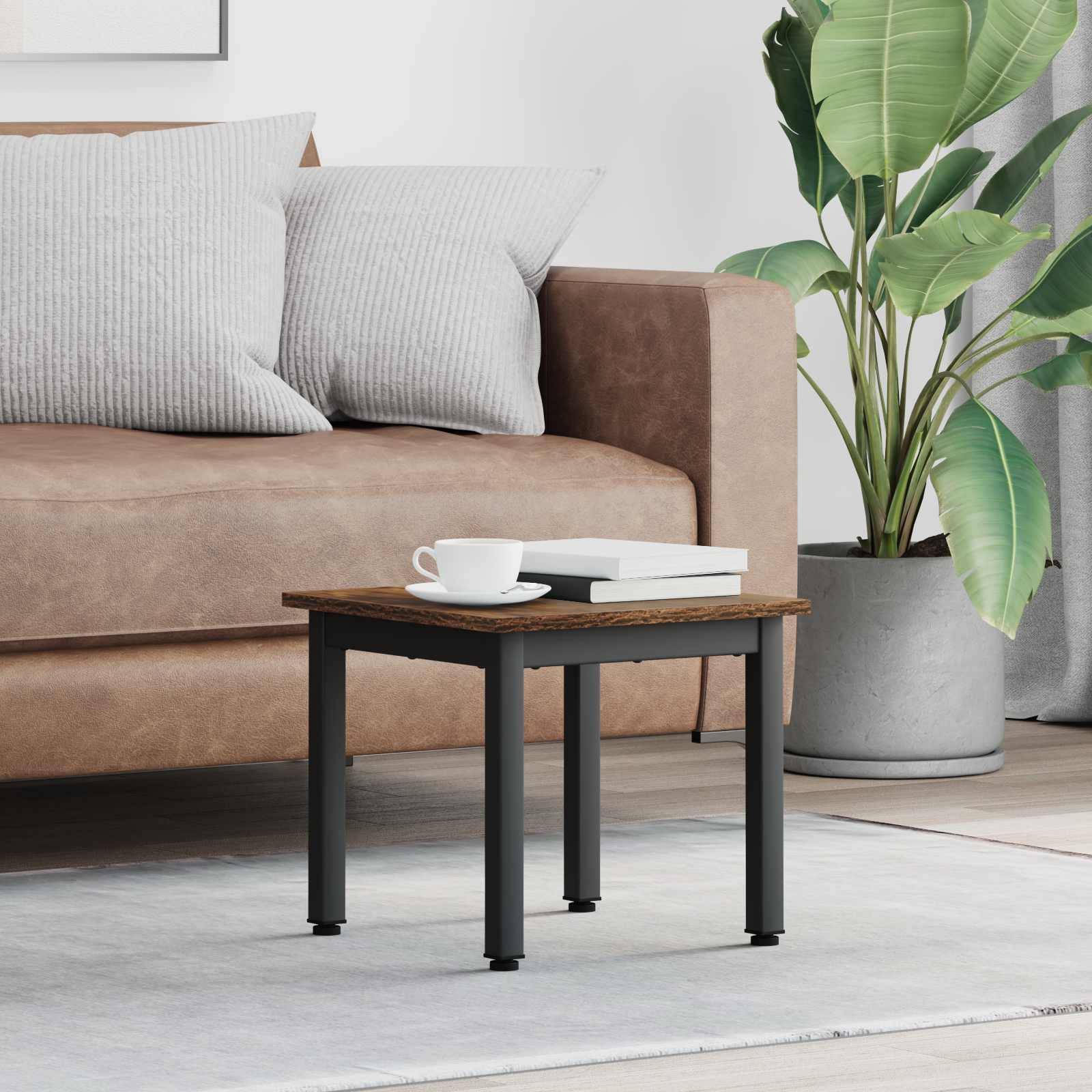 Ein gemütliches Wohnzimmer zeigt ein braunes Sofa mit grauen Kissen, einen kleinen Holzcouchtisch mit einer weißen Tasse und eine Topfpflanze in der Nähe.