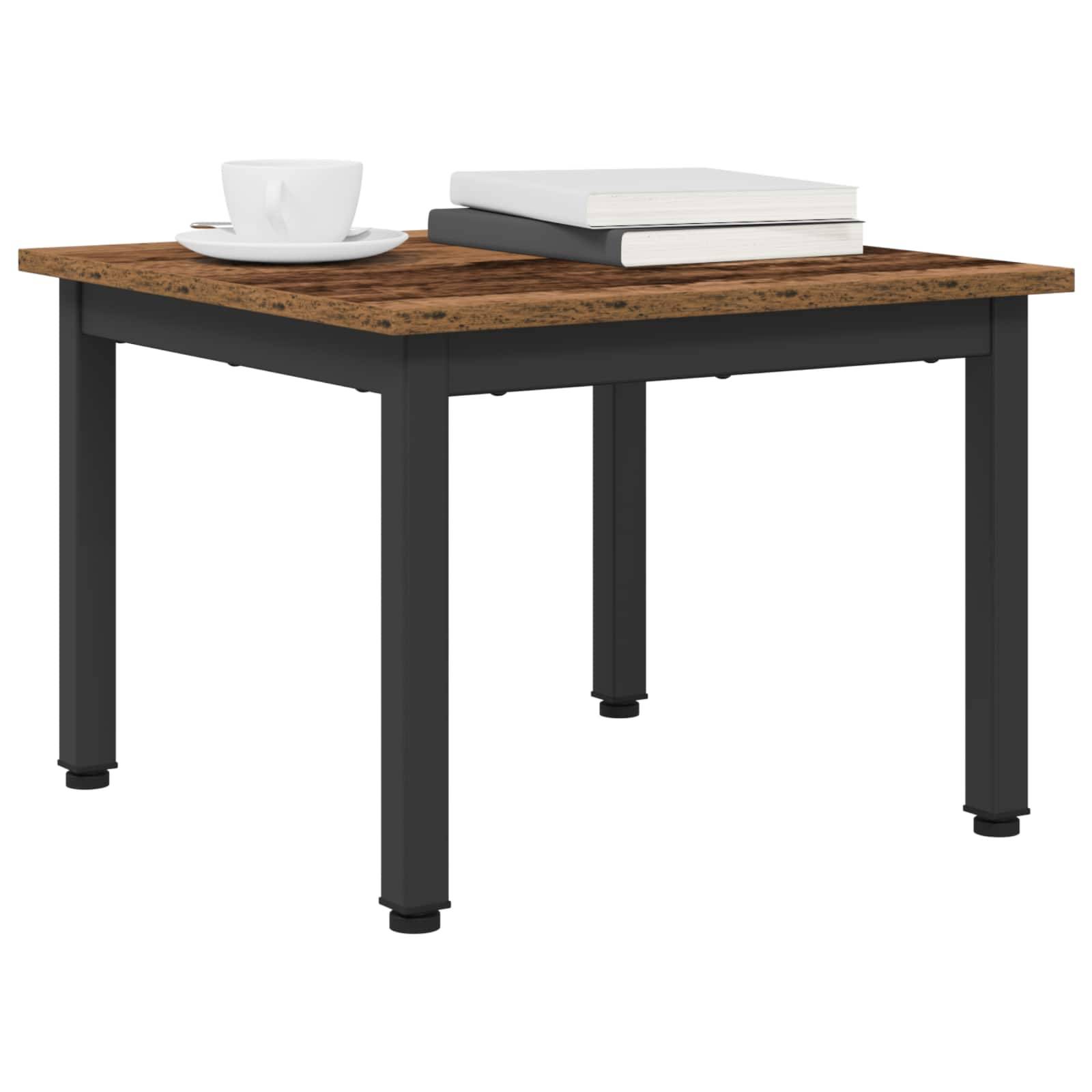 Ein kleiner quadratischer Holztisch mit schwarzen Beinen, auf dem ein Stapel von zwei Büchern und eine weiße Kaffeetasse stehen.