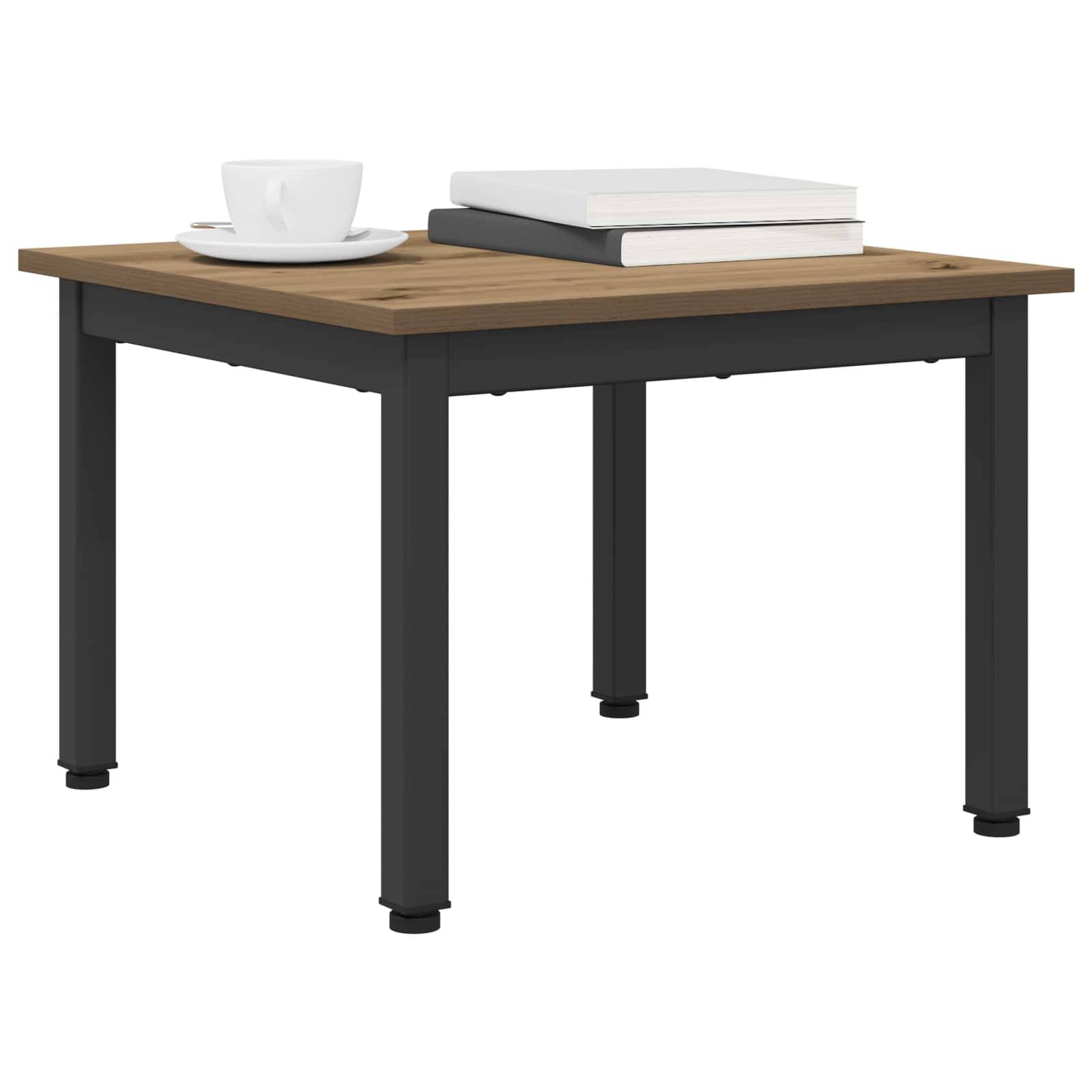 Ein quadratischer Holztisch mit schwarzen Beinen. Auf dem Tisch stehen eine weiße Kaffeetasse mit Untertasse und zwei aufeinandergestapelte Bücher.
