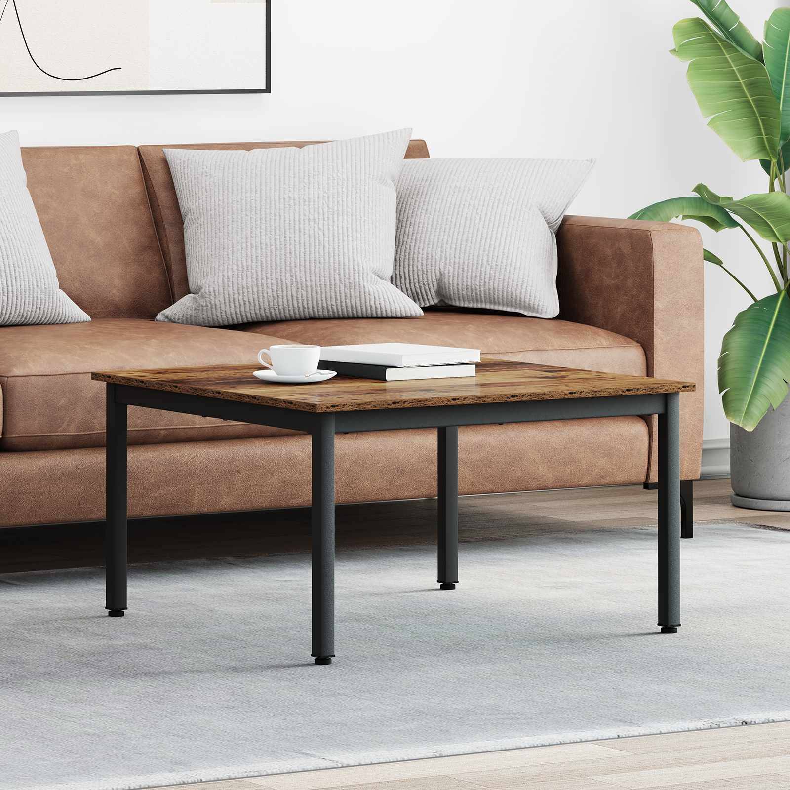 Ein braunes Sofa mit hellgrauen Kissen steht in einem modernen Wohnzimmer. Ein Holzkaffeetisch trägt eine weiße Tasse und ein Buch. Eine Pflanze steht in der Nähe.