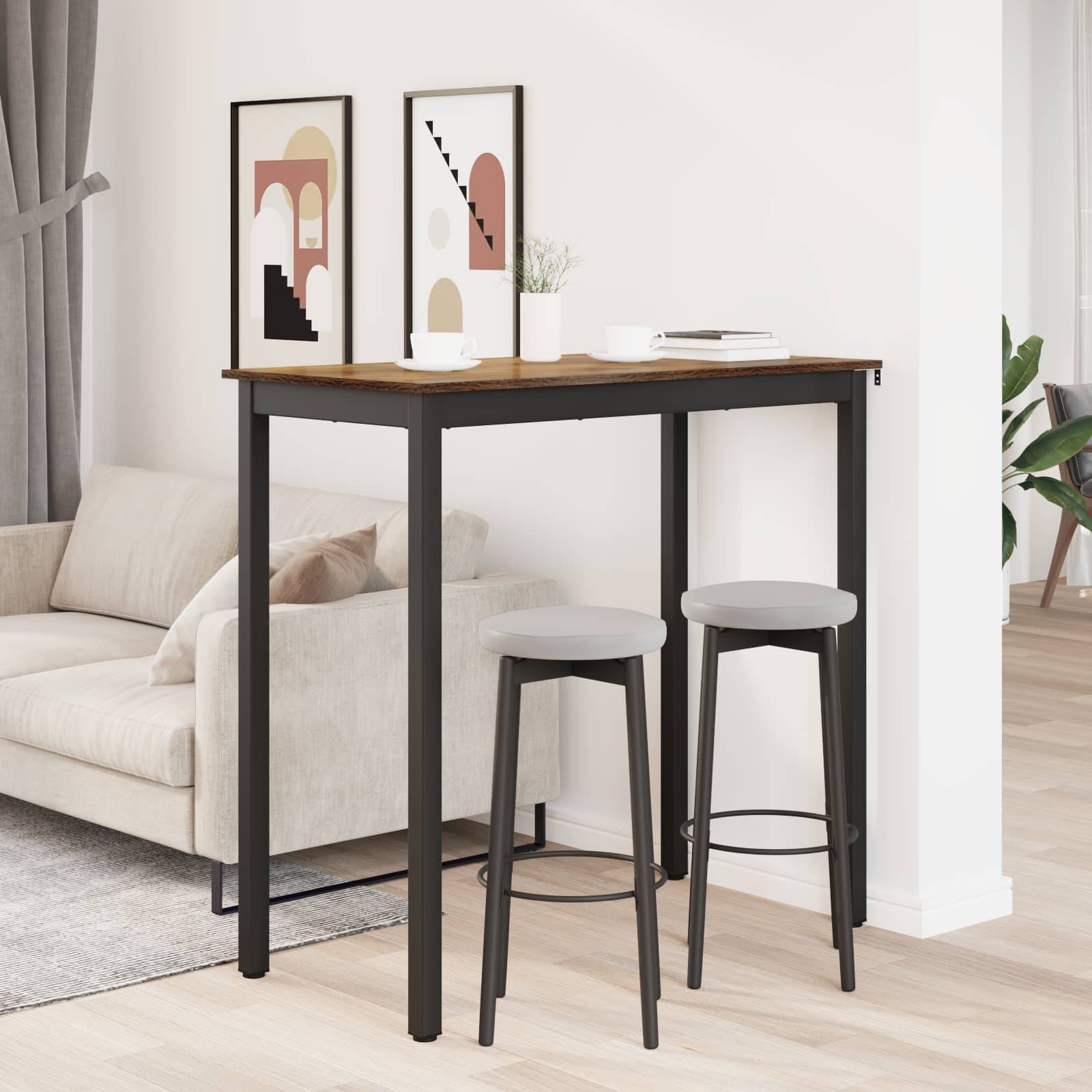 Ein minimalistischer Wohnbereich mit einem beigen Sofa, einem hohen schwarzen Tisch mit Holzplatte, zwei Hockern, gerahmter abstrakter Kunst an der Wand und einem Vorhang.