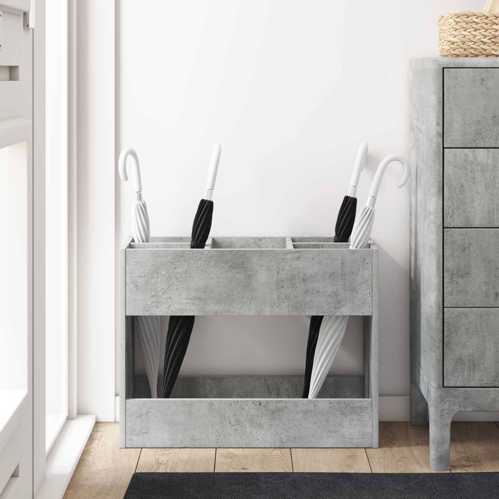 Ein Schirmständer aus Beton hält drei Schirme neben einem Schubladenschrank in einem minimalistischen, modernen Raum mit weißen Wänden und hellem Holzboden.