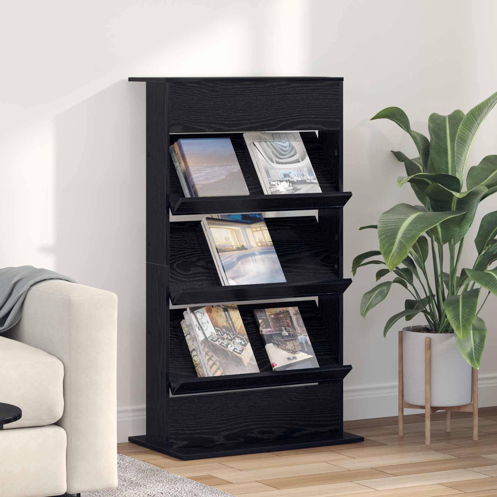 Schwarzes Holz-Magazinregal mit mehreren ausgestellten Zeitschriften neben einer Topfpflanze in einem hellen Wohnzimmer.