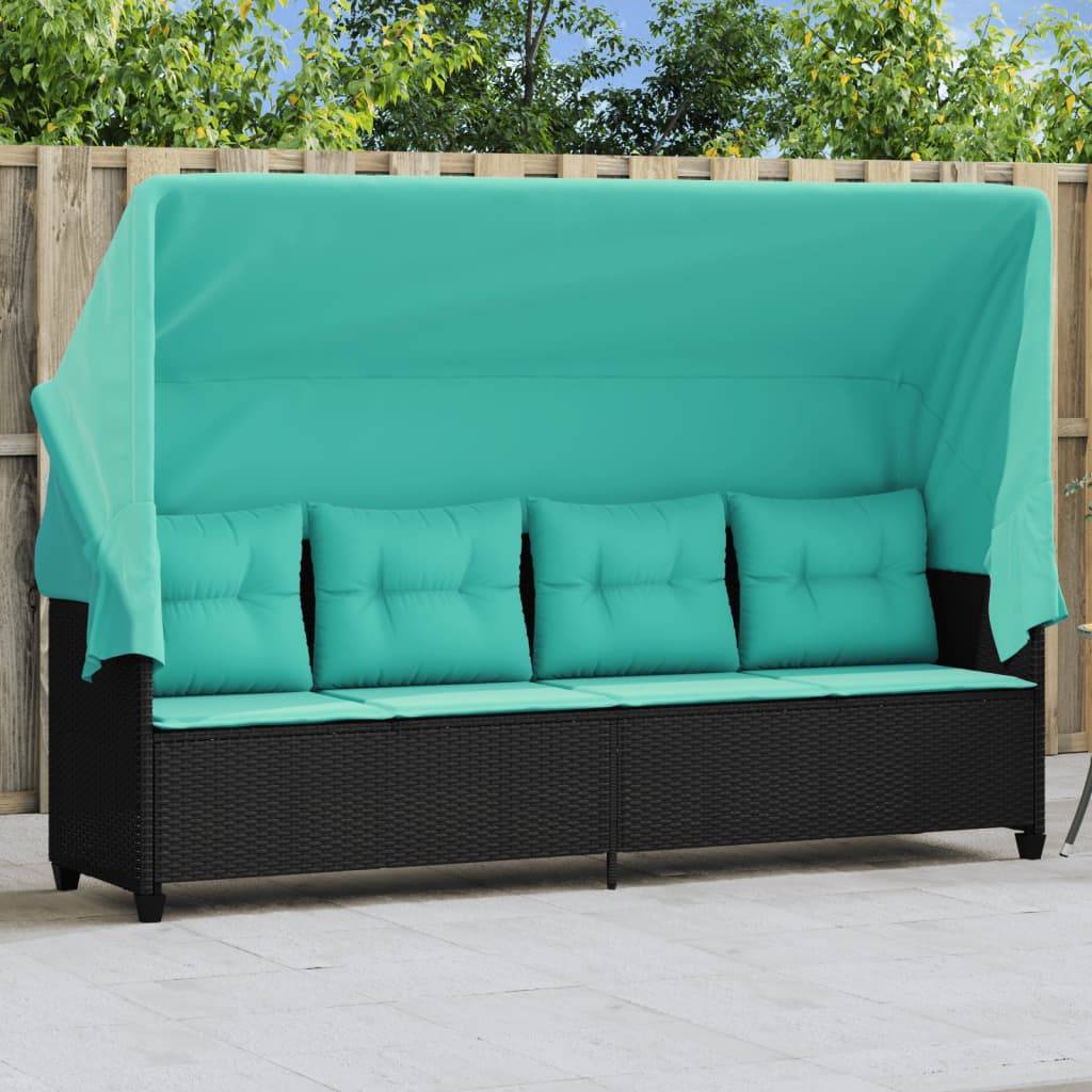 Eine schwarze Outdoor-Couch mit blauen Kissen, geschützt von einem passenden Sonnensegel, vor einem Holzzaun und Bäumen in einem Terrassenbereich.