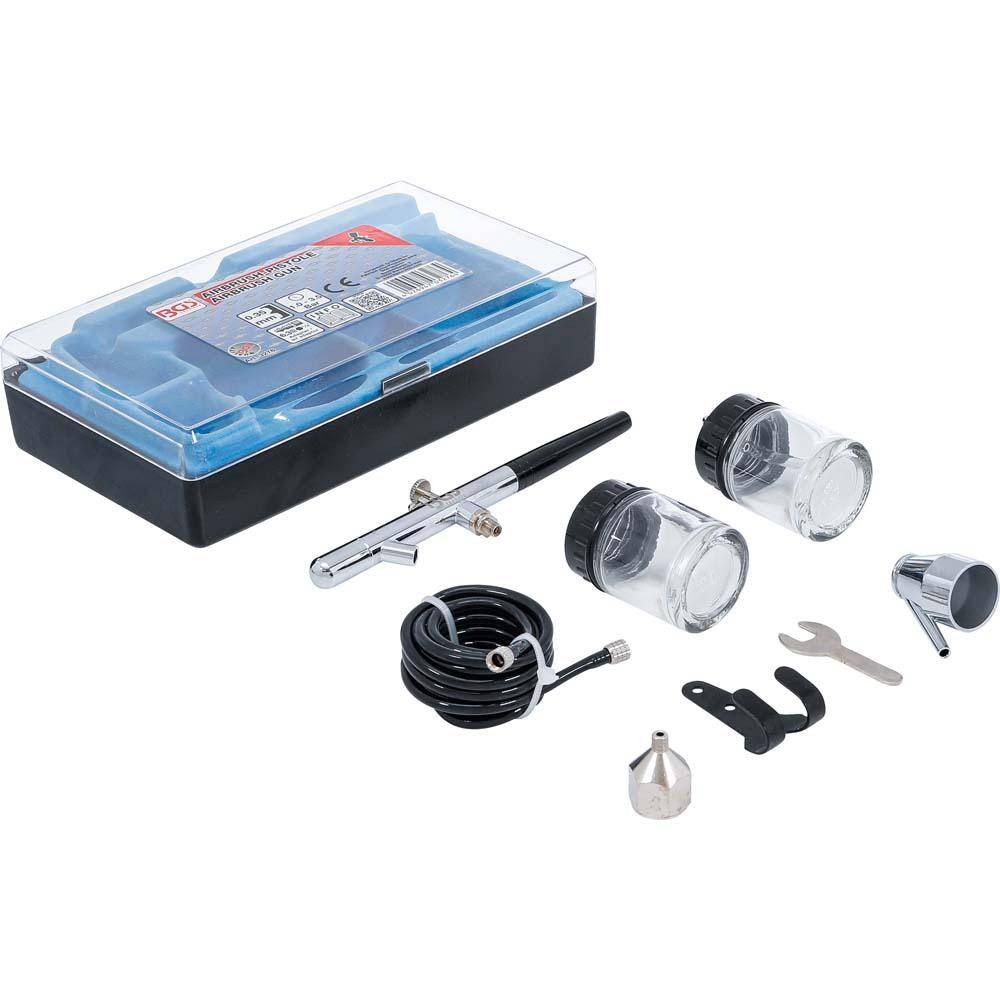 Airbrush-Set mit Düse, Schlauch, Farbgläsern und Schraubenschlüsseln in schwarzem Kunststoffkoffer. Enthält verschiedene Zubehörteile für Airbrush-Aufgaben.