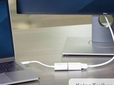 Ein Laptop, der über einen kleinen USB-C-Adapter an einem Schreibtisch an einen Monitor angeschlossen ist. Der Monitor zeigt eine teilweise Ansicht, die größtenteils außerhalb des Bildschirms liegt.