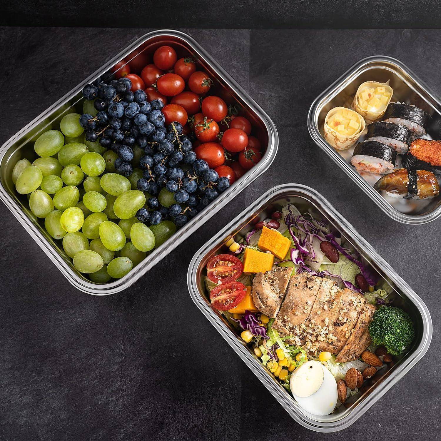 Lunchbox mit gegrilltem Hähnchen, Cocktailtomaten, Brokkoli, Mais und einem hartgekochten Ei. Beilagen sind Trauben, Blaubeeren und Sushi.