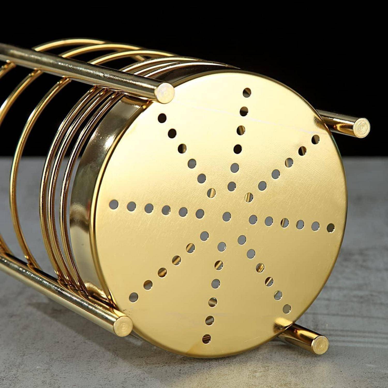 Ein goldfarben-metallfarbener kreisförmiger Metallständer mit perforierten Löchern, die in einem Sternmuster angeordnet sind, liegt auf seiner Seite und dient zum Halten von Gegenständen.