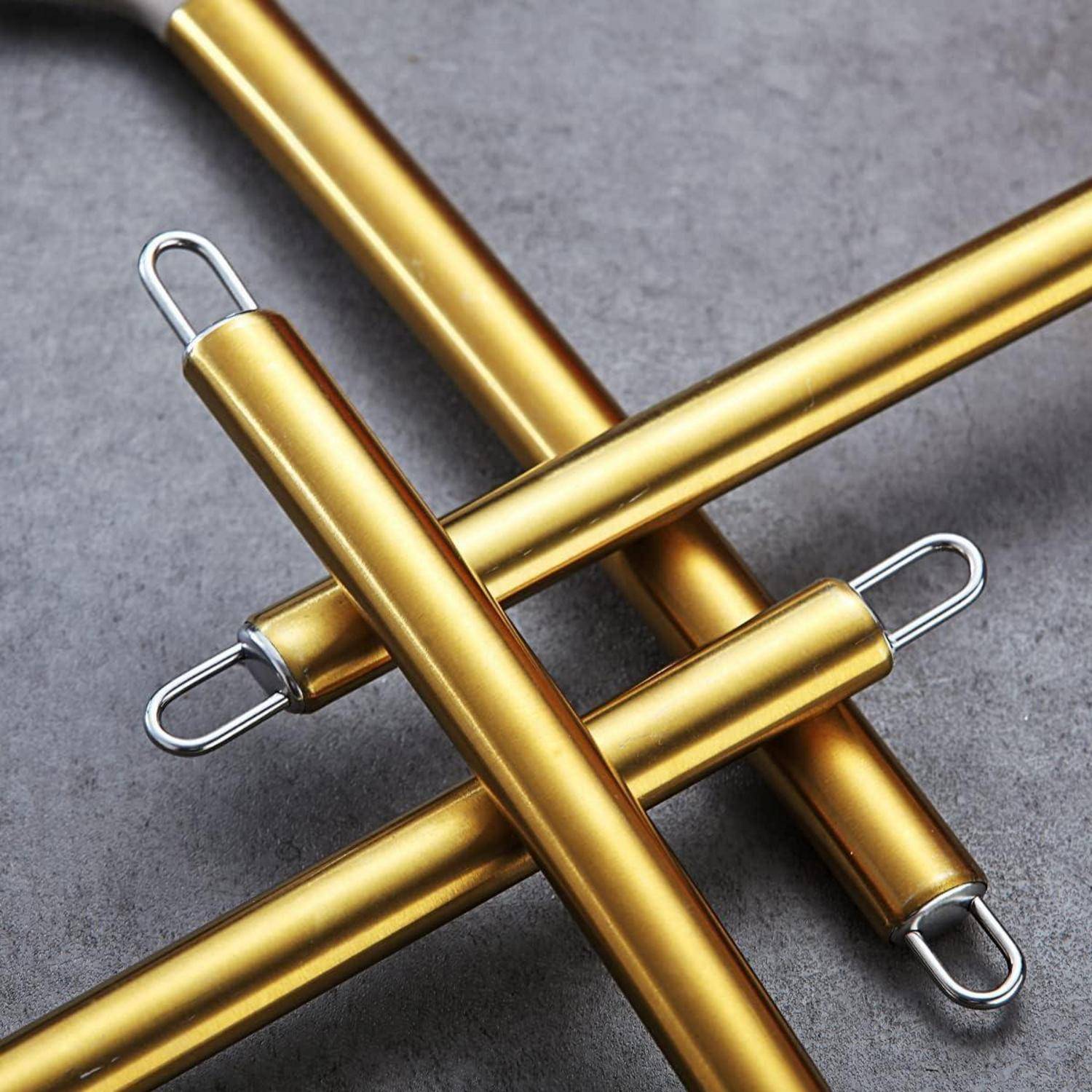 Vier goldene metallische Griffe, jeder mit einer geschlungenen Endung, sind diagonal auf einem grauen Hintergrund angeordnet. Sie wirken industriell oder werkzeugähnlich.