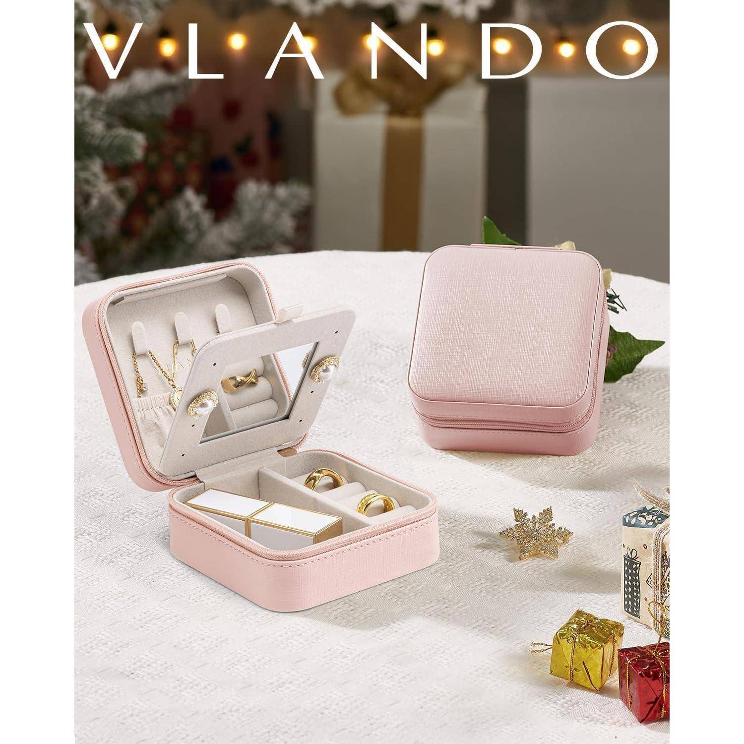 Eine rosa Schmuckschatulle mit Ringen und Halsketten, die auf einem Tisch ausgestellt ist, umgeben von kleinen eingepackten Geschenken und Dekorationen.