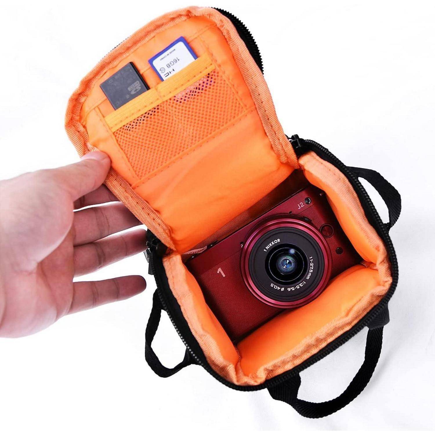 Eine rote Kamera in einem orangefarbenen Etui. Eine Hand hält das Etui offen und zeigt die Speicherkartensteckplätze.