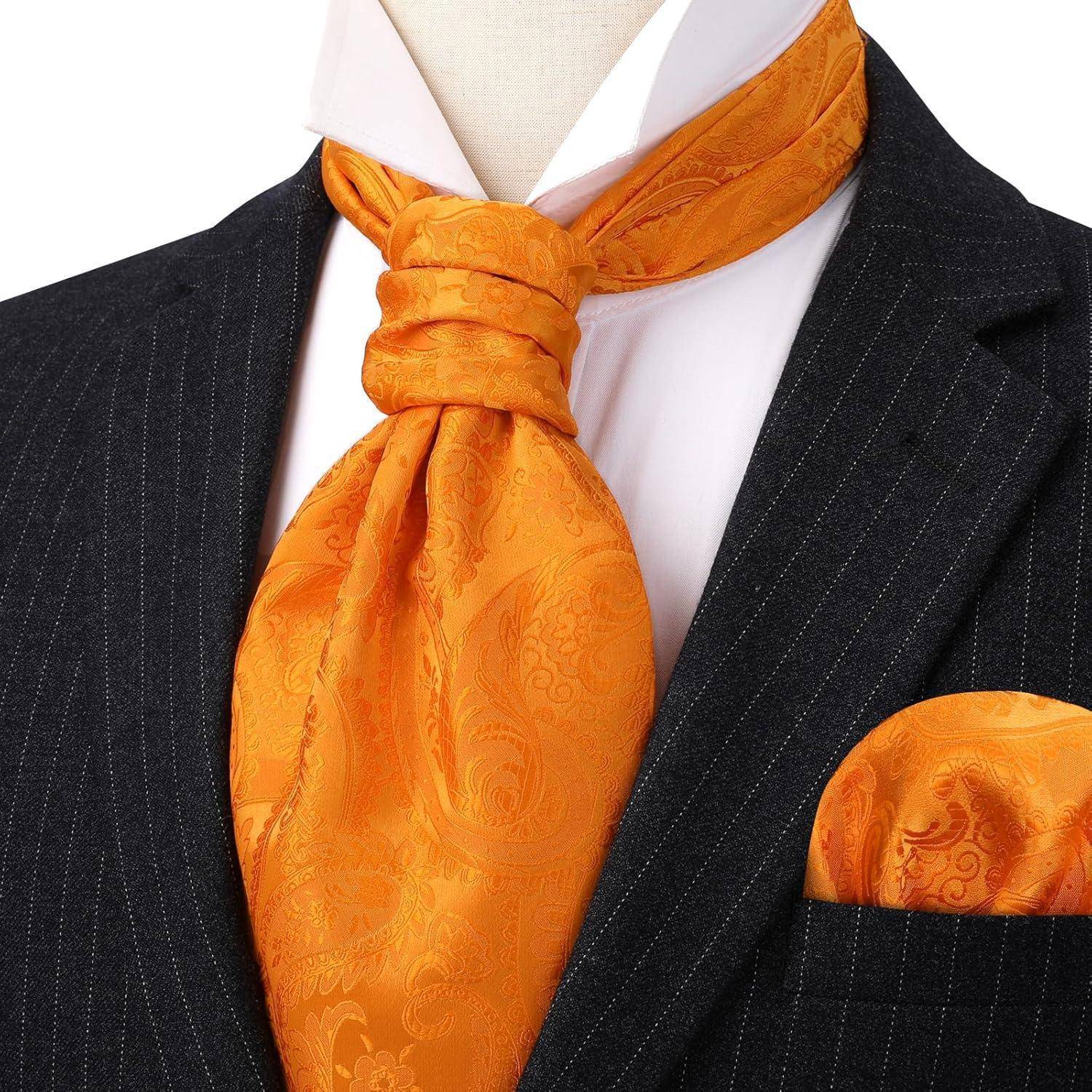 Eine Schaufensterpuppe präsentiert einen eleganten schwarzen Nadelstreifenanzug mit einem weißen Hemd, versehen mit einer kunstvoll geknoteten hellorangefarbenen Seidenkrawatte und einem passenden Einstecktuch.