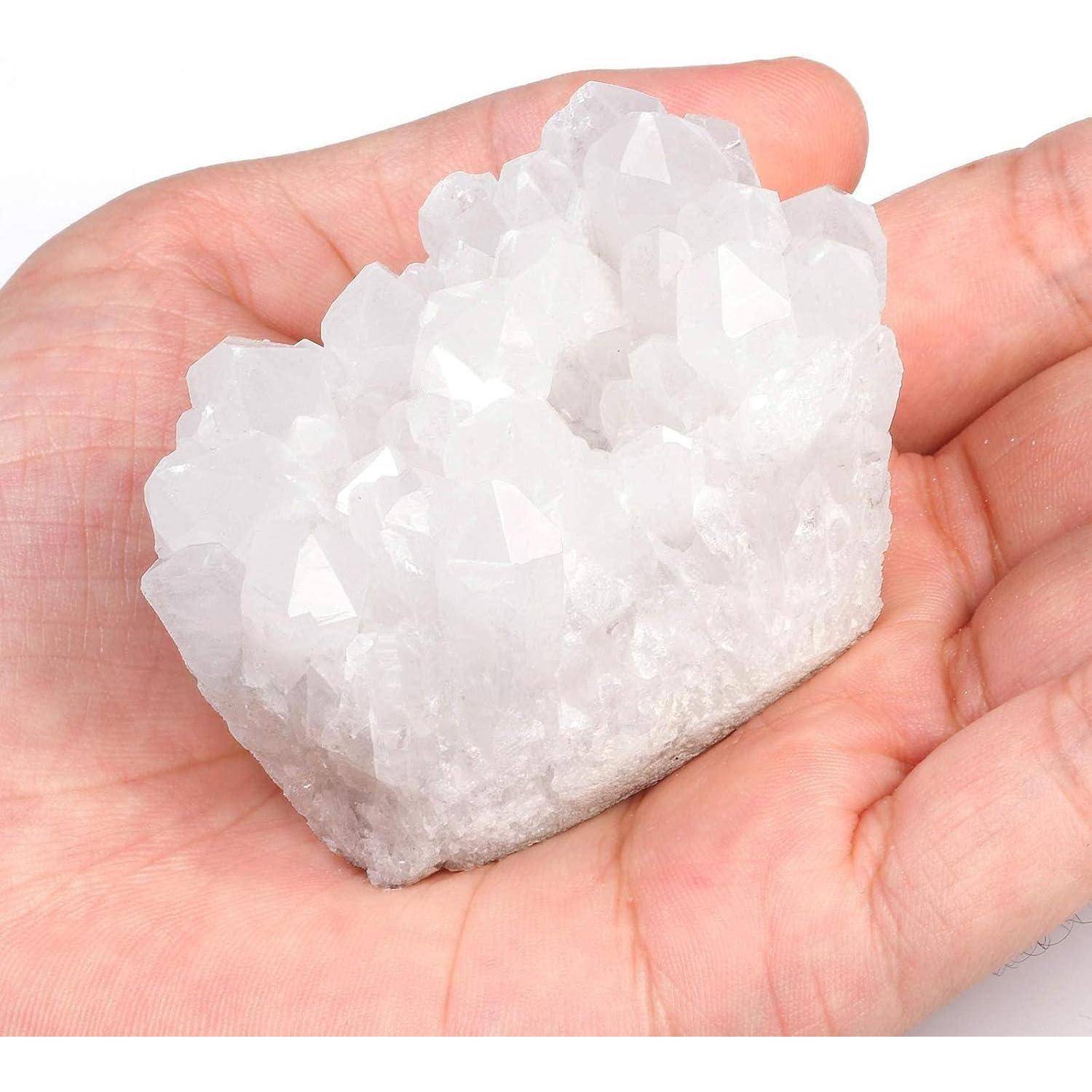 Eine Hand, die einen Cluster aus transparenten, weißen Kristallen hält, die das Licht reflektieren.
