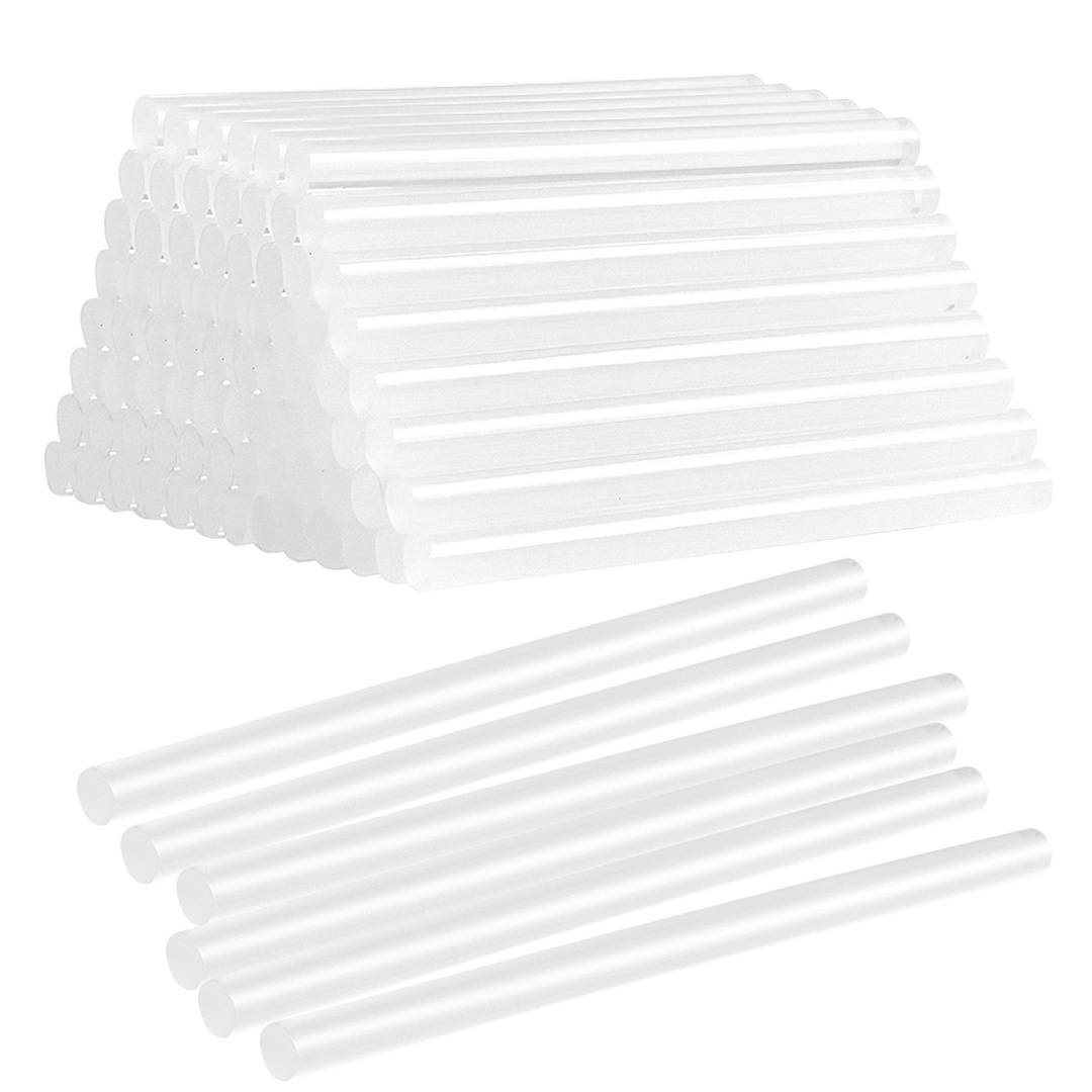 Ein Stapel weißer Klebestifte ist in einer Pyramidenform angeordnet. Darunter sind einige einzelne Stifte parallel zueinander ausgelegt.
