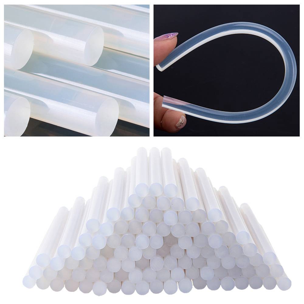 Nahaufnahme von transparenten Silikonklebesticks; einer wird gebogen und zeigt Flexibilität. Ein Bündel dieser Sticks ist in einer Pyramidenform gestapelt.