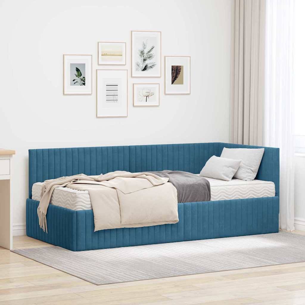 Ein modernes Zimmer mit einem blau gepolsterten Tagesbett, beigen und grauen Decken, einem weißen Schreibtisch und gerahmten Wandkunstwerken. Heller grauer Teppich auf dem Boden.