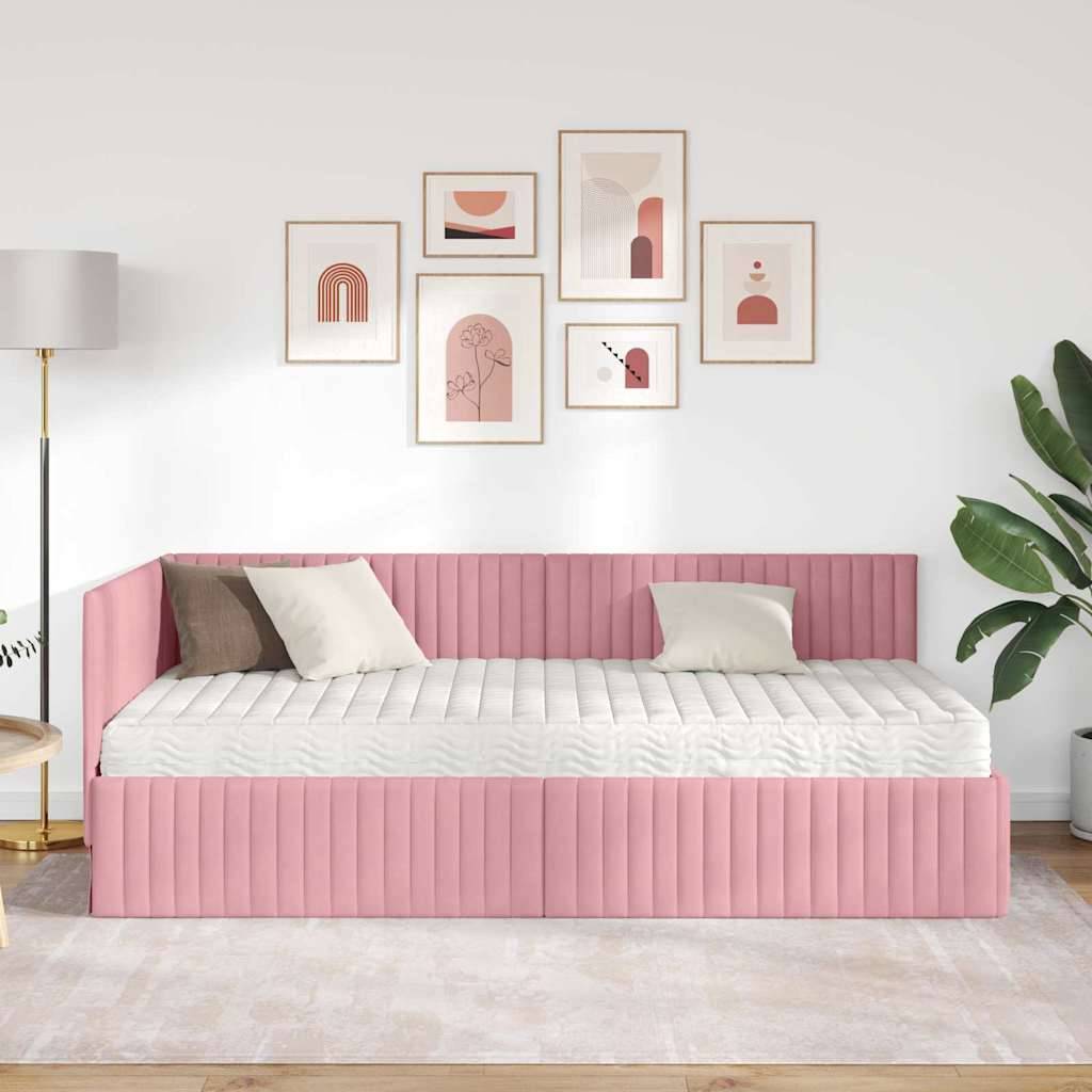 Ein moderner Raum mit einer rosa bezogenen Tageliege, weißen und beigen Kissen, abstrakten Kunstwerken an der Wand, einer Stehlampe und einer Topfpflanze.