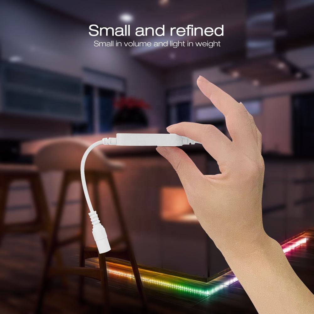 Eine Hand, die ein kompaktes, weißes elektronisches Gerät mit einem Kabel hält. Im Hintergrund ist eine sanft beleuchtete, moderne Küche zu sehen. Text lautet: „Klein und elegant. Klein im Volumen und leicht im Gewicht.