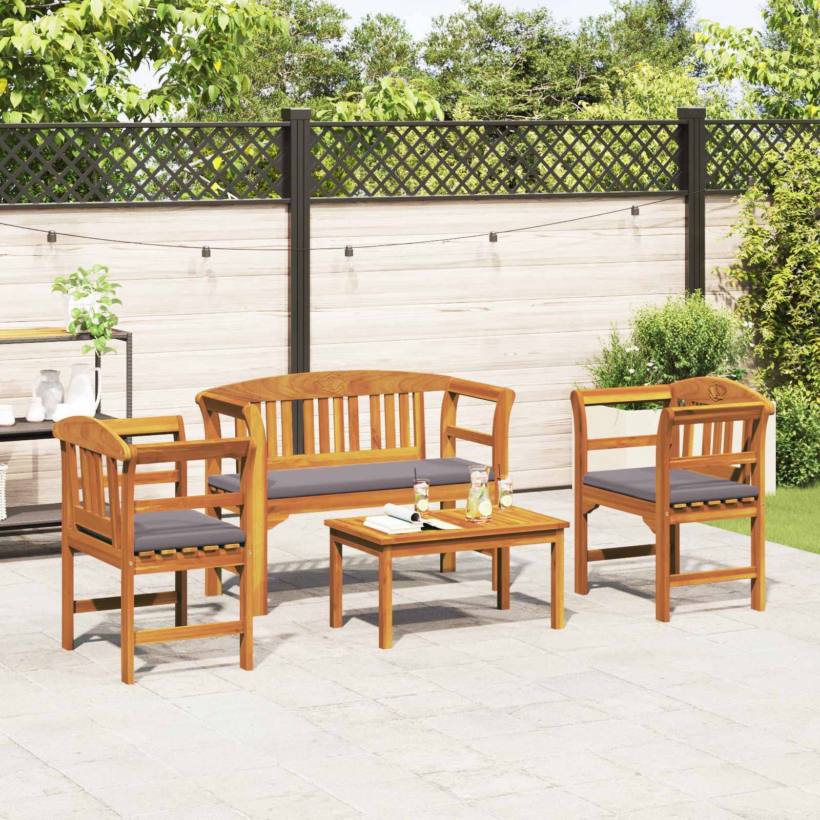 Outdoor-Sitzgruppe aus Holz bestehend aus einer Bank, zwei Stühlen und einem Couchtisch auf einer Terrasse. Ein hölzerner Sichtschutzzaun und Grünpflanzen im Hintergrund.
