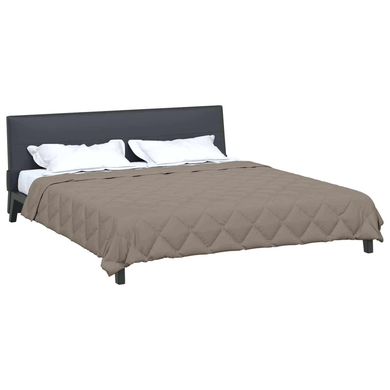 Ein ordentlich gemachtes Bett mit einem gepolsterten grauen Kopfteil, weißen Kissen und einer beigen gesteppten Tagesdecke.