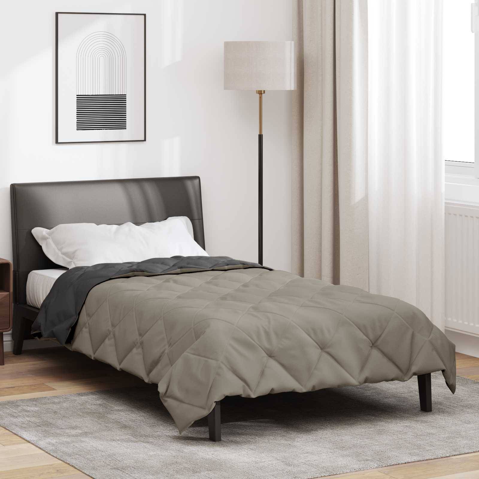 Ein sorgfältig gemachtes Bett in einem modernen Schlafzimmer mit einer grauen Steppdecke, schwarzem Kopfteil und einer Stehlampe daneben. Minimalistische Kunstwerke hängen an der Wand.