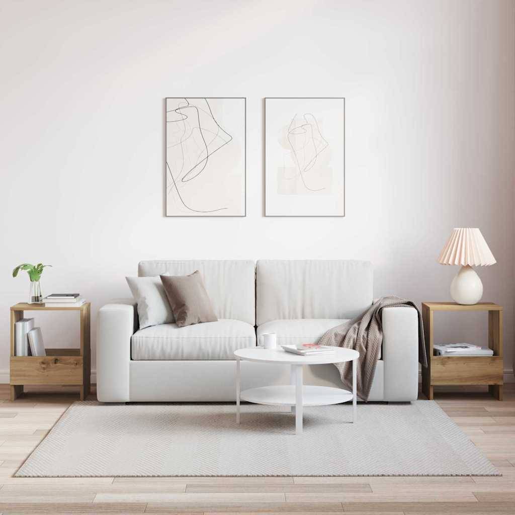 Ein minimalistisches Wohnzimmer mit einem weißen Sofa, zwei abstrakten Kunstwerken, Holzseitentischen, einem weißen Couchtisch und einer Lampe rechts.