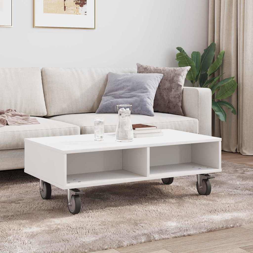 Ein moderner Wohnbereich mit einem weißen Sofa, grauen und beigen Kissen, einem weißen Couchtisch auf Rollen und einer Topfpflanze in der Ecke.