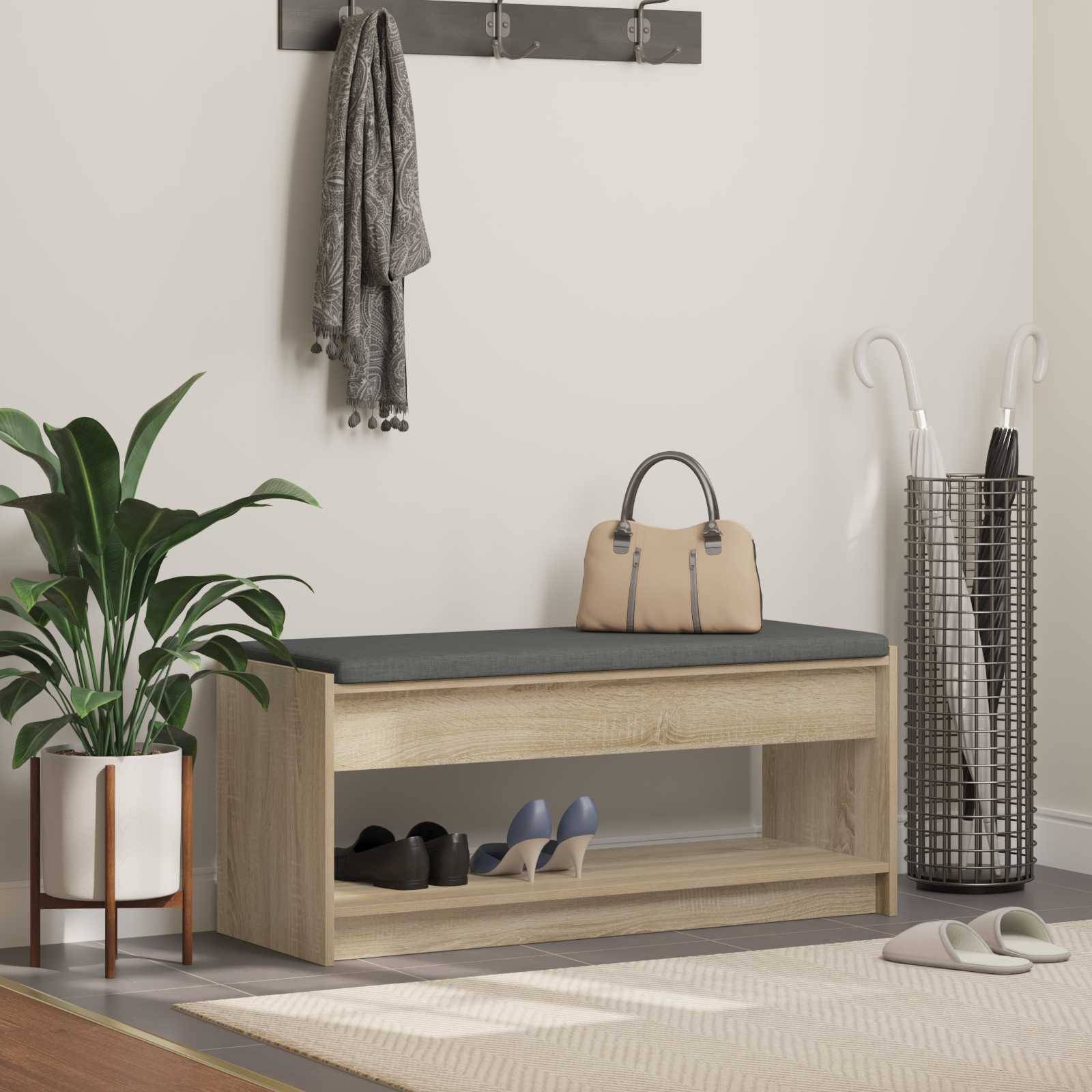 Ein moderner Eingangsbereich mit einer Holzbank, grauem Kissen, einer Wandgarderobe mit Schals, einer Topfpflanze und einem dekorativen Korb mit Regenschirmen.