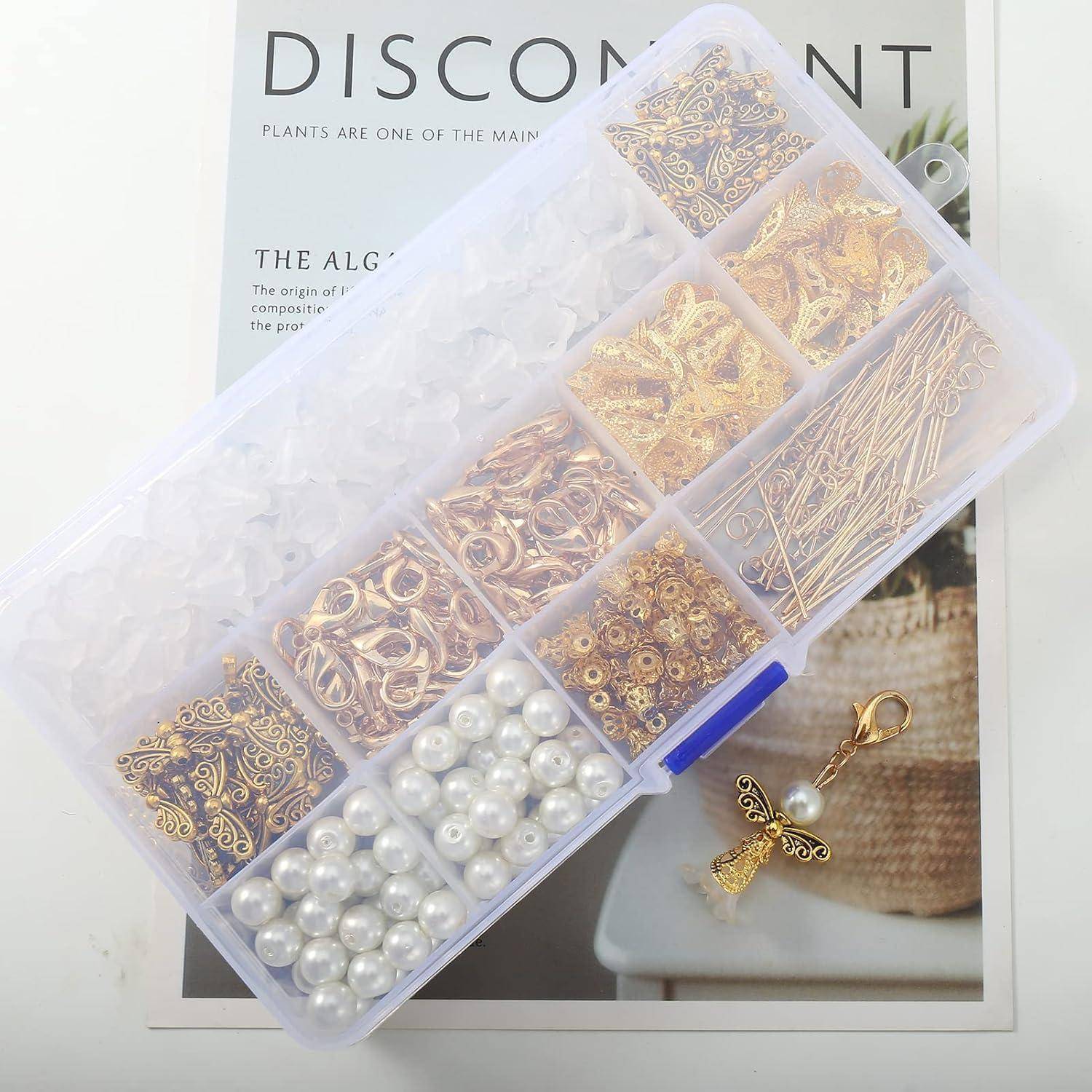 Eine durchsichtige Aufbewahrungsbox mit Fächern enthält Gold- und perlmuttfarbene Schmuckherstellungsmaterialien. Ein engelsförmiger Schlüsselanhänger liegt in der Nähe auf einer Zeitseite.