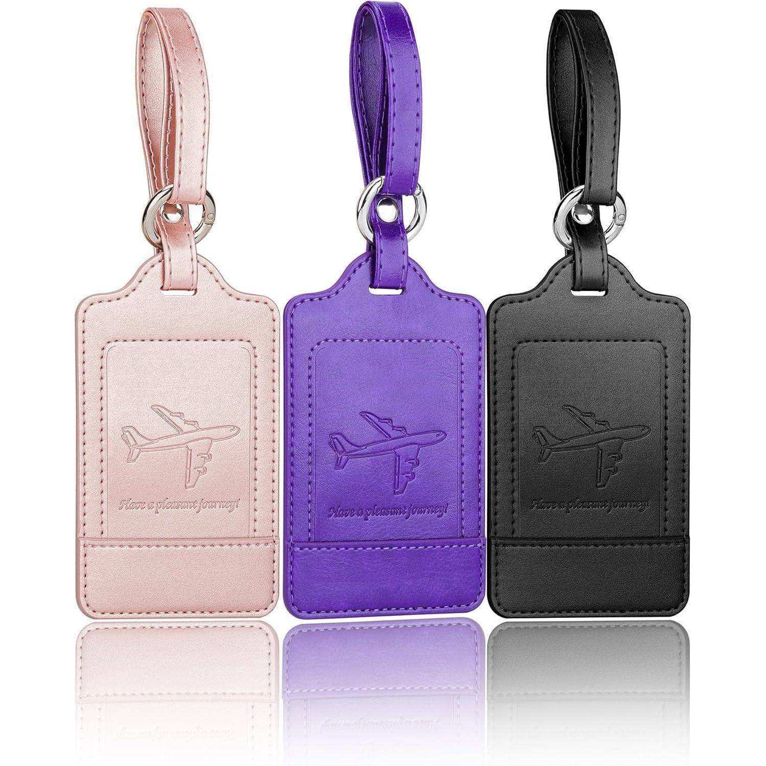 Drei Gepäckanhänger mit Flugzeug-Motiv; Farben sind Pink, Lila und Schwarz. Die Anhänger haben eine Schlaufenöse und sind geprägt.