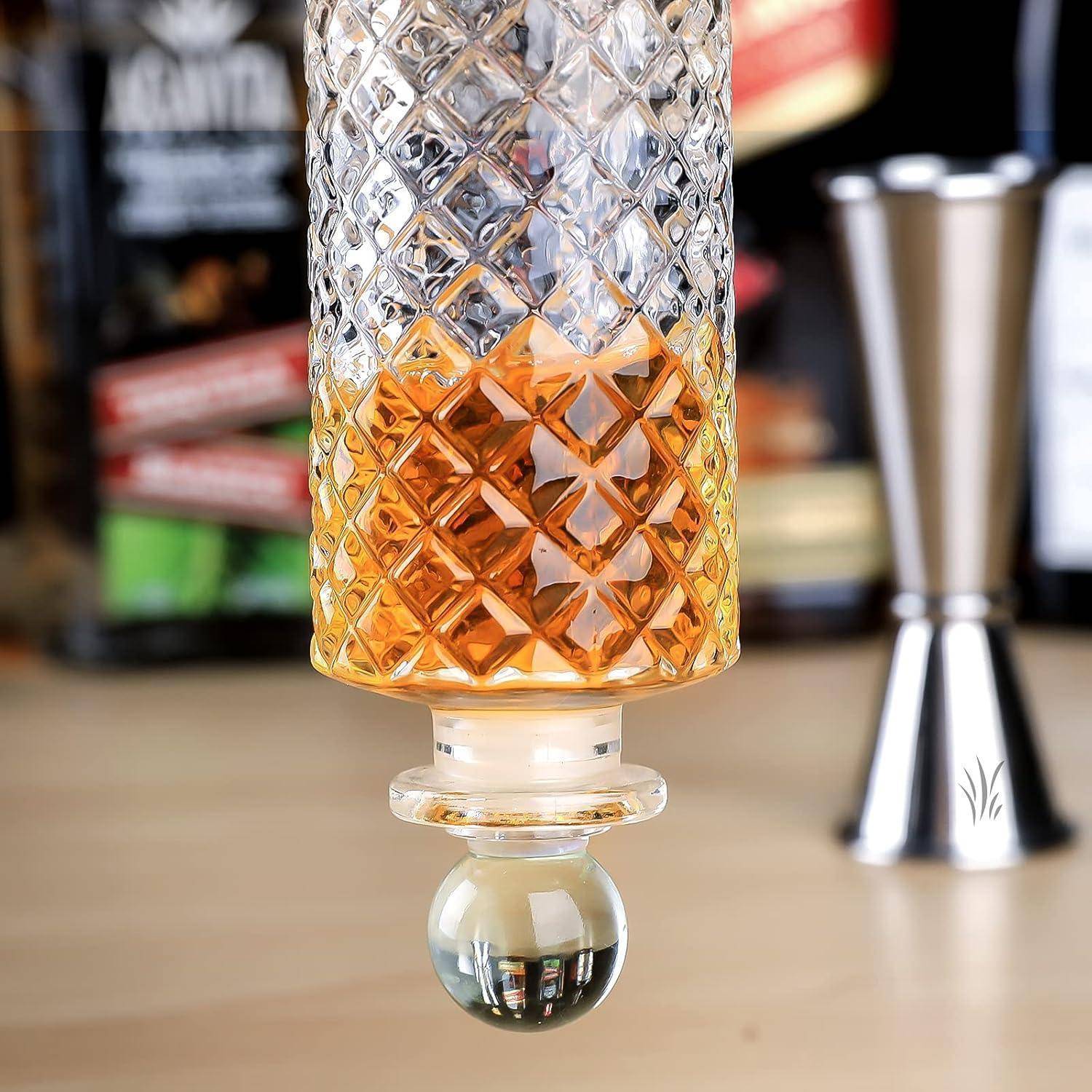 Eine dekorative Glasflasche mit einem kunstvollen Muster enthält eine bernsteinfarbene Flüssigkeit vor einem unscharfen Bardekors.