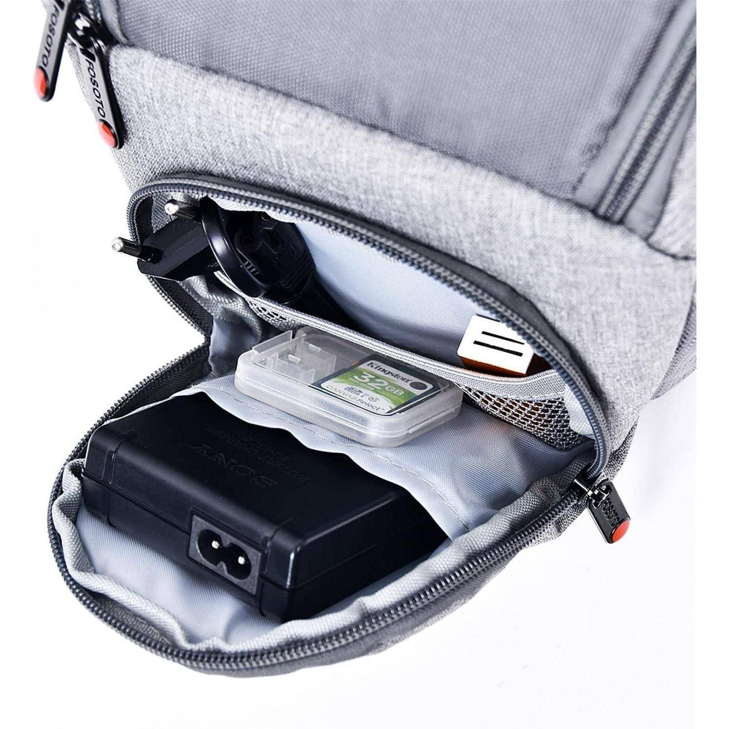 Eine graue Rucksacktasche ist geöffnet und gibt verschiedene elektronische Zubehörteile preis, darunter ein schwarzer Adapter, ein runder Stecker und kleinere Geräte.