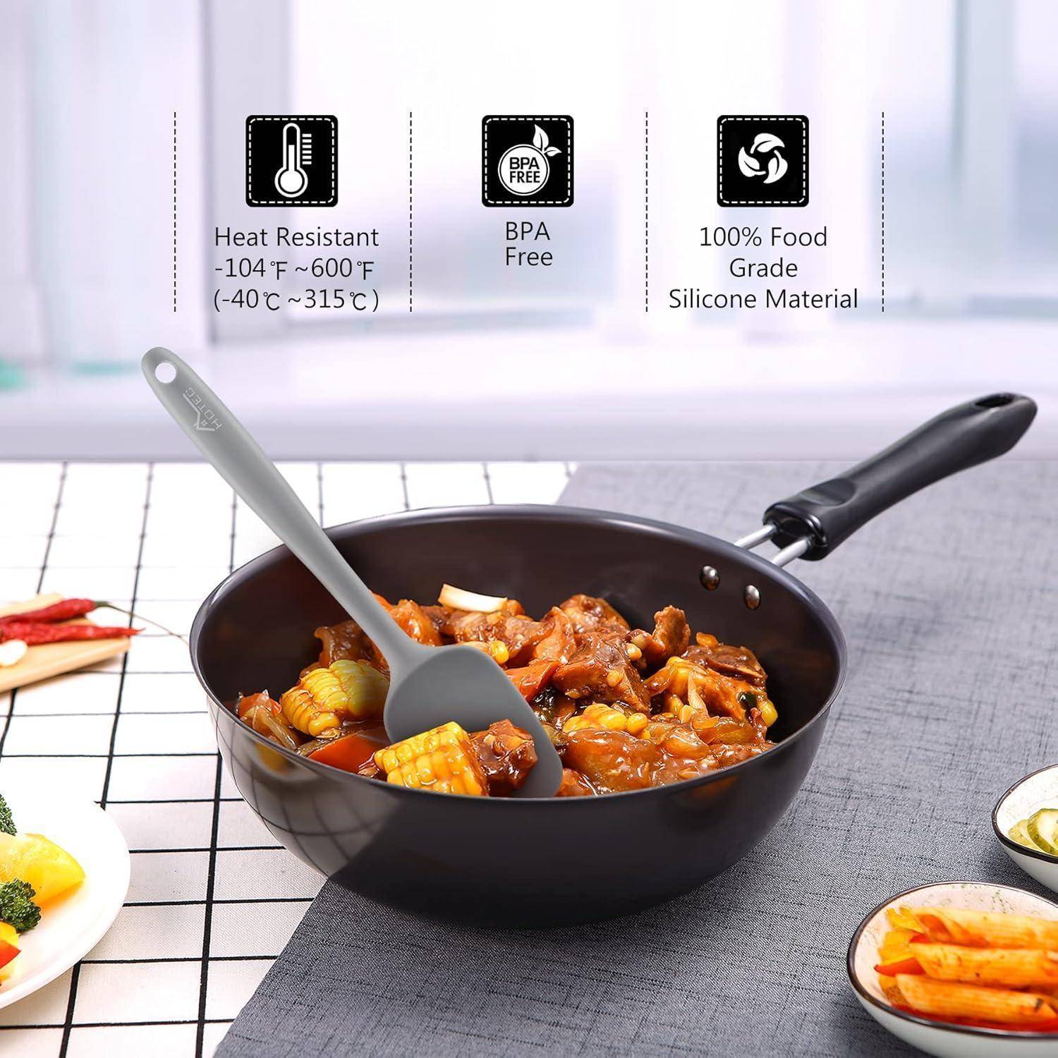 Eine Sautépfanne gefüllt mit einem gekochten Gericht, das Mais, Paprika und Fleisch enthält. Etiketten weisen darauf hin, dass sie hitzebeständig, BPA-frei und aus lebensmittelechtem Silikon hergestellt ist.