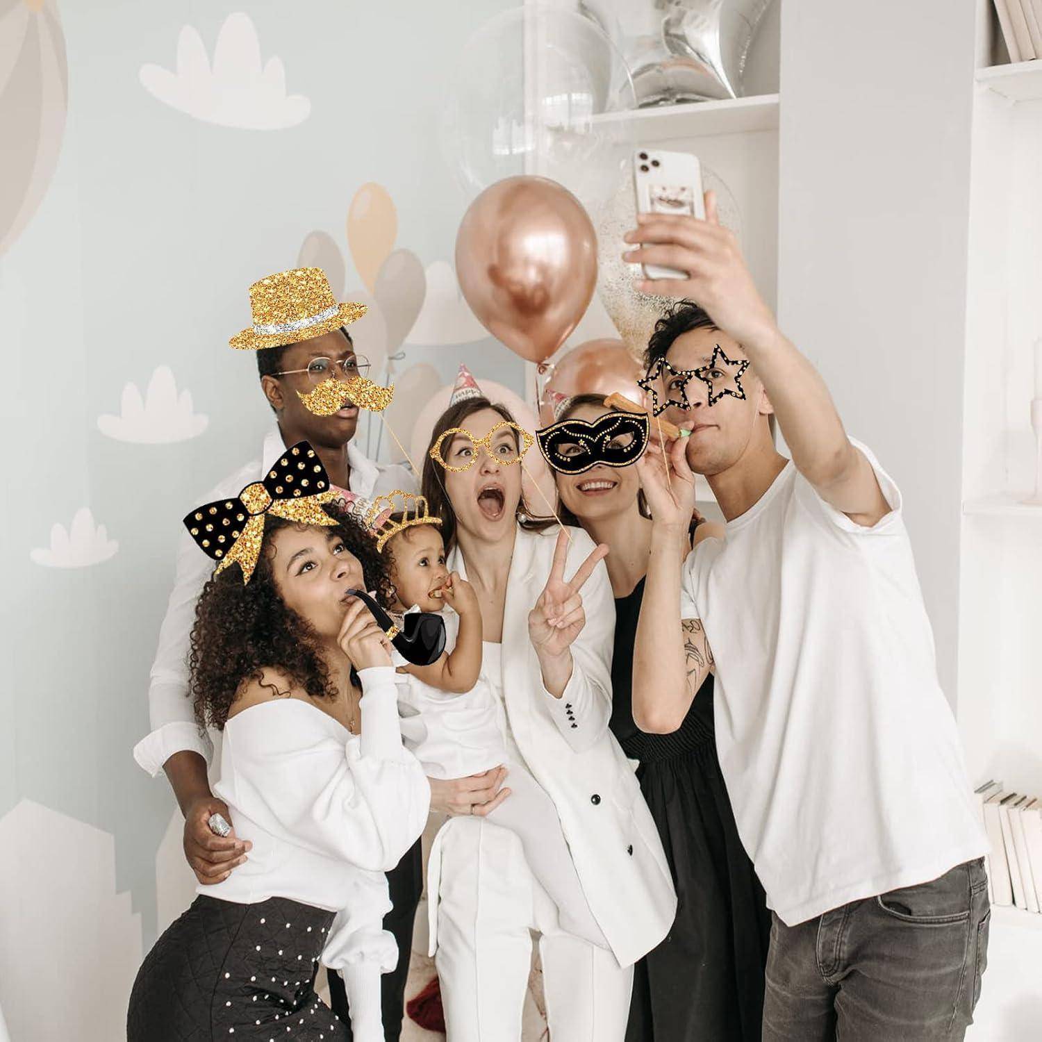 Eine Gruppe von Menschen, festlich gekleidet, macht ein Selfie, trägt Partyhüte und lustige Brillen und feiert in einem dekorierten Raum.